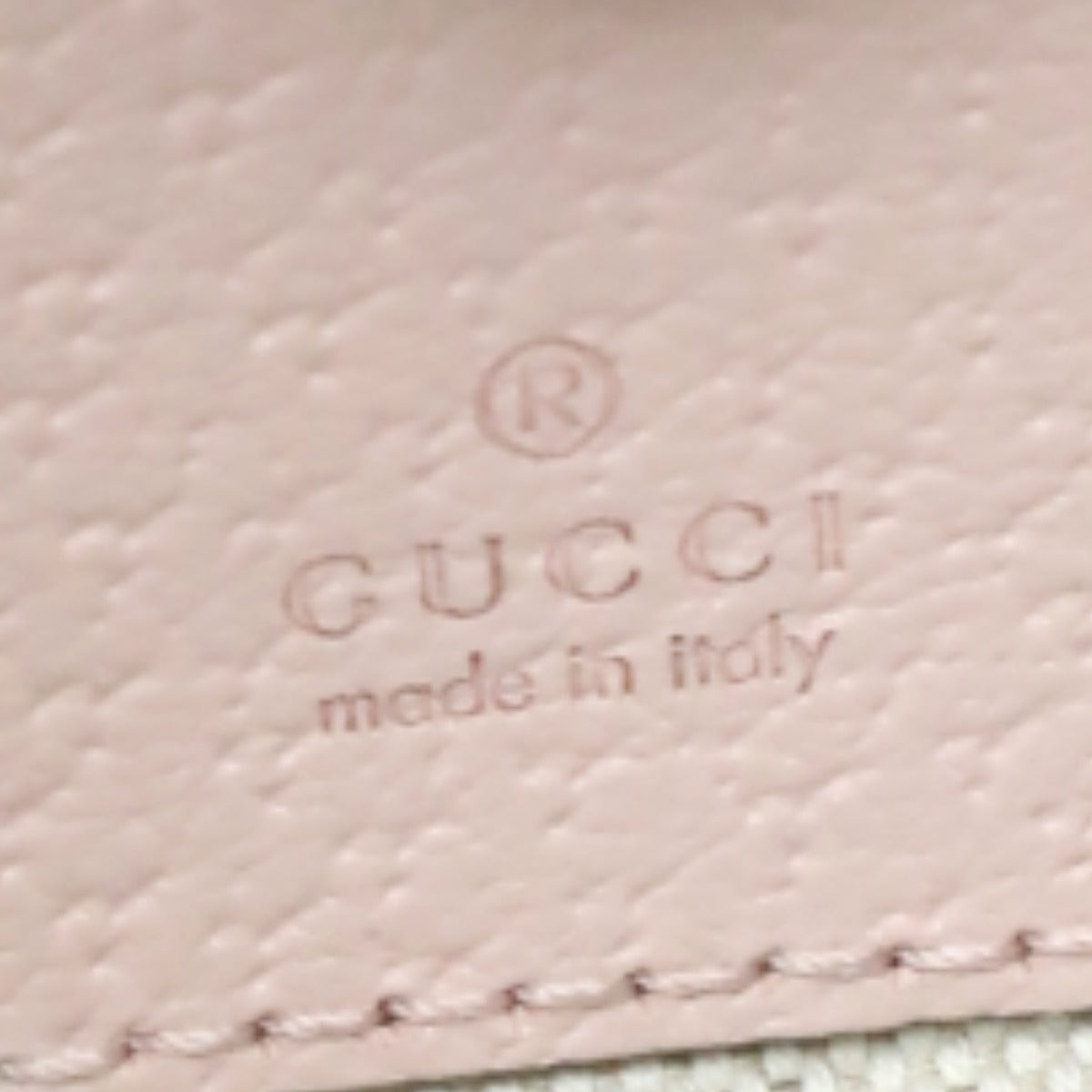 Close-up of Gucci logo on a pink textured surface