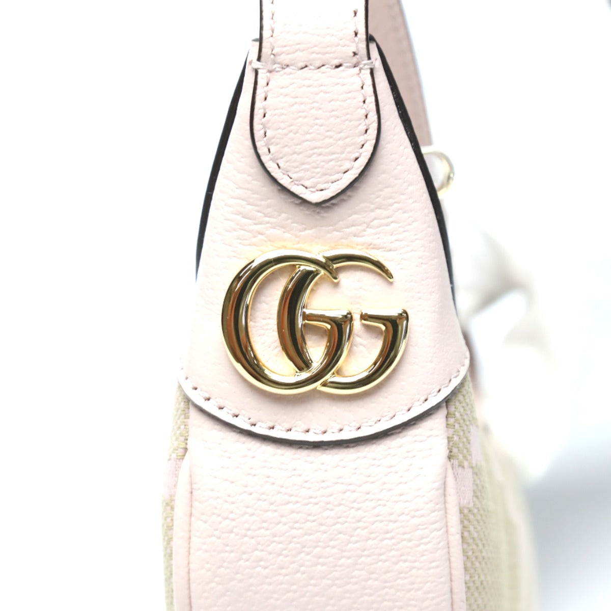 Close-up of a pink handbag with a gold Gucci logo on a white background