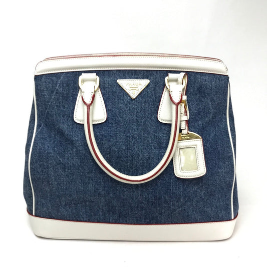 Blue denim bag with white accents and a bottle charm on a white background