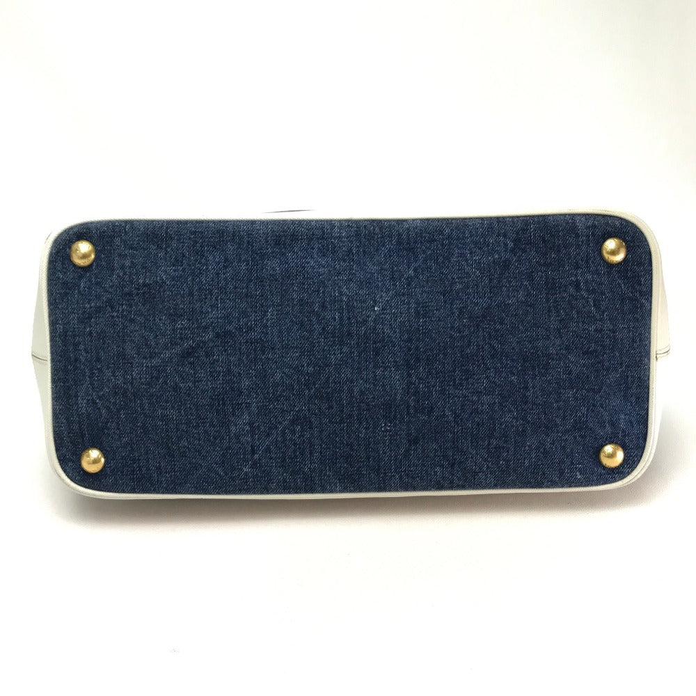 Blue denim clutch bag with gold studs on a white background