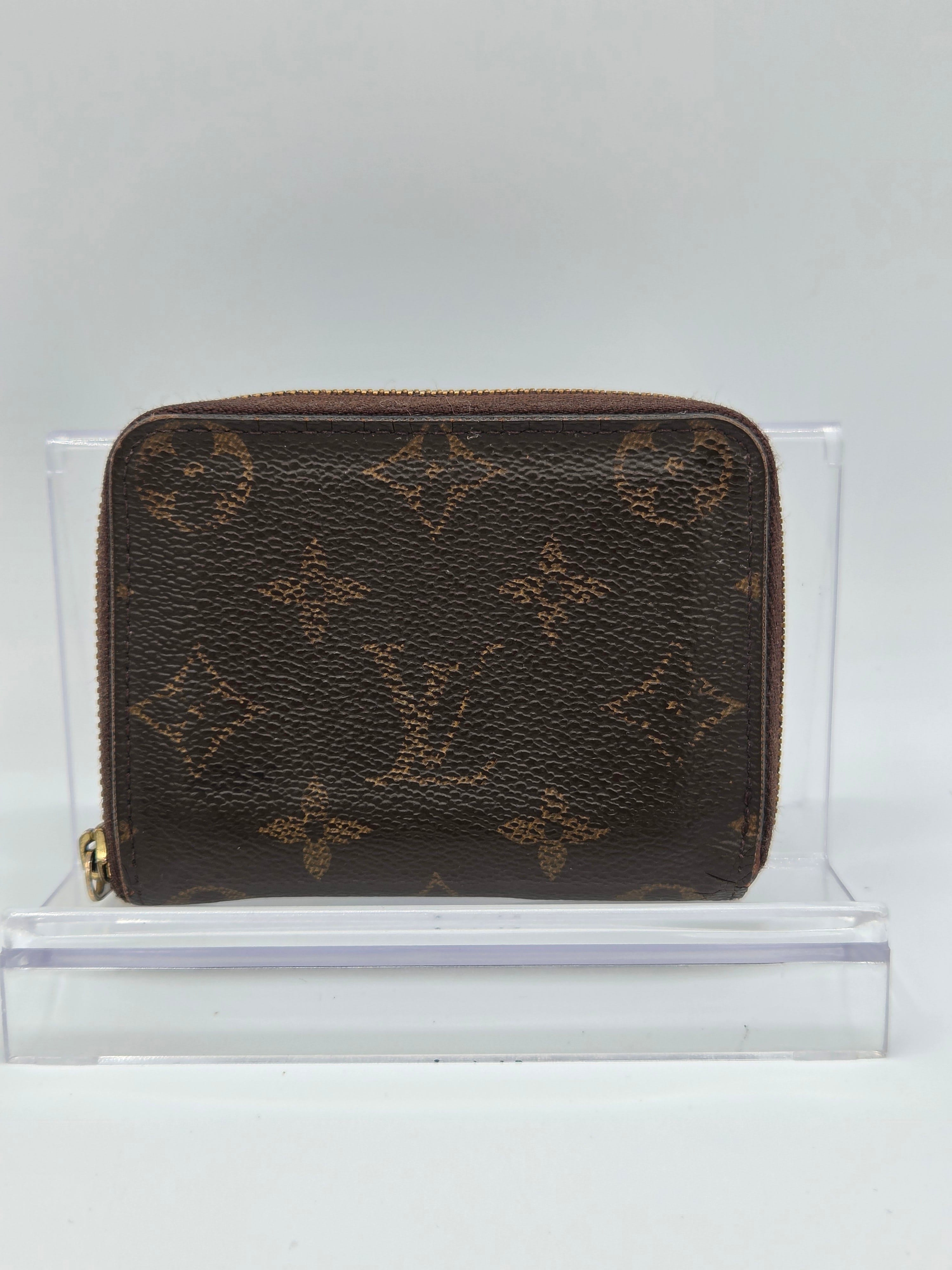 Brown patterned wallet in a clear display case on a light gray background