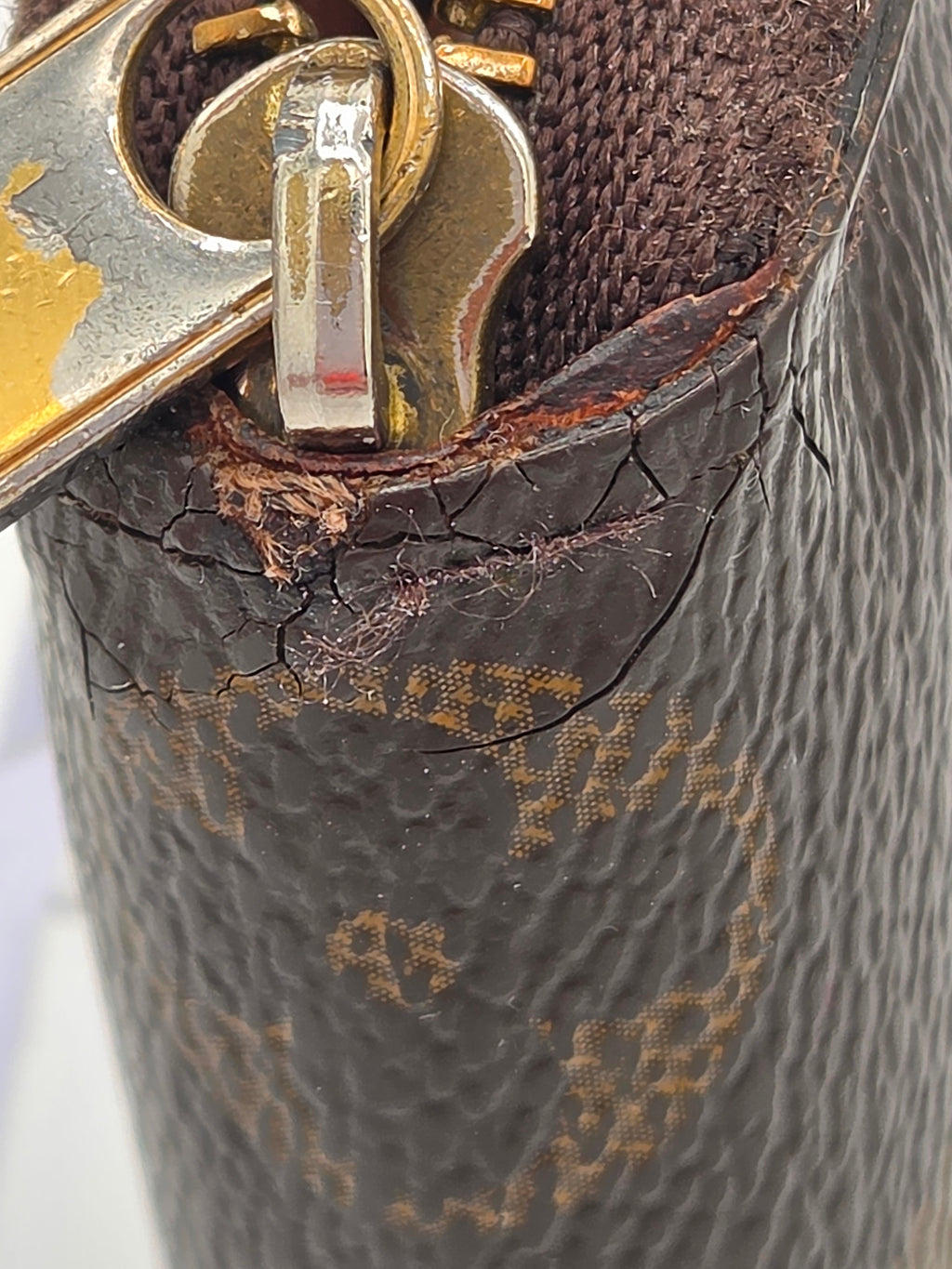 Close-up of a damaged brown leather handbag with visible scuffs and a gold clasp.