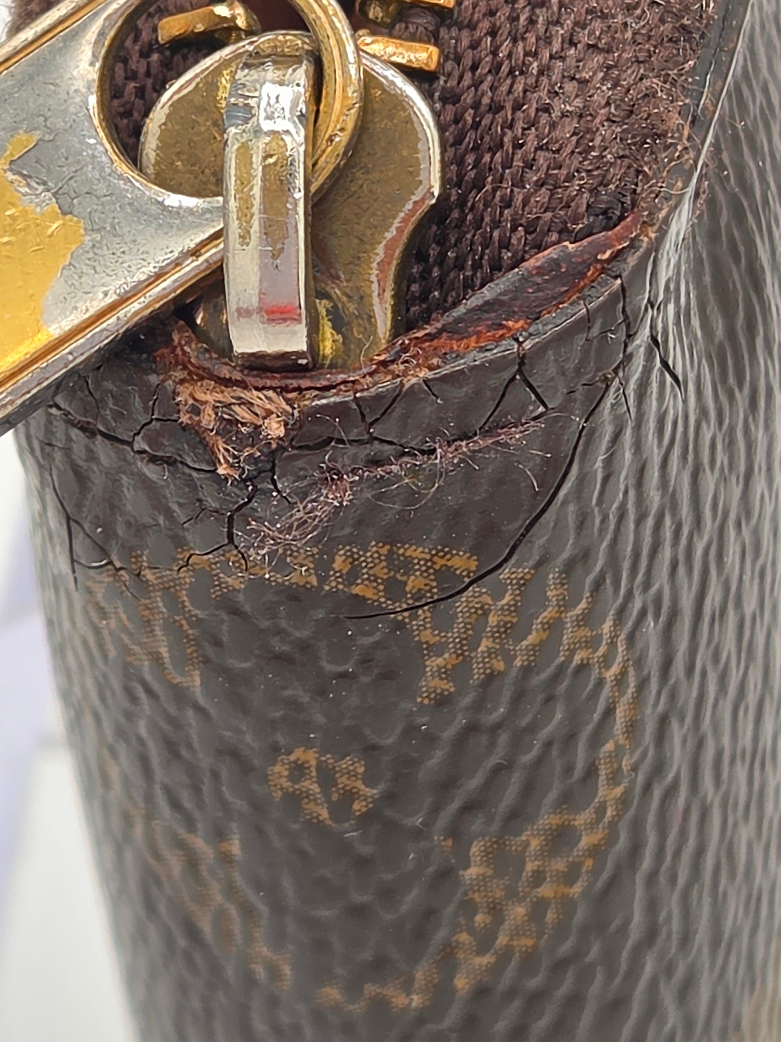 Close-up of a damaged brown leather handbag with visible scuffs and a gold clasp.