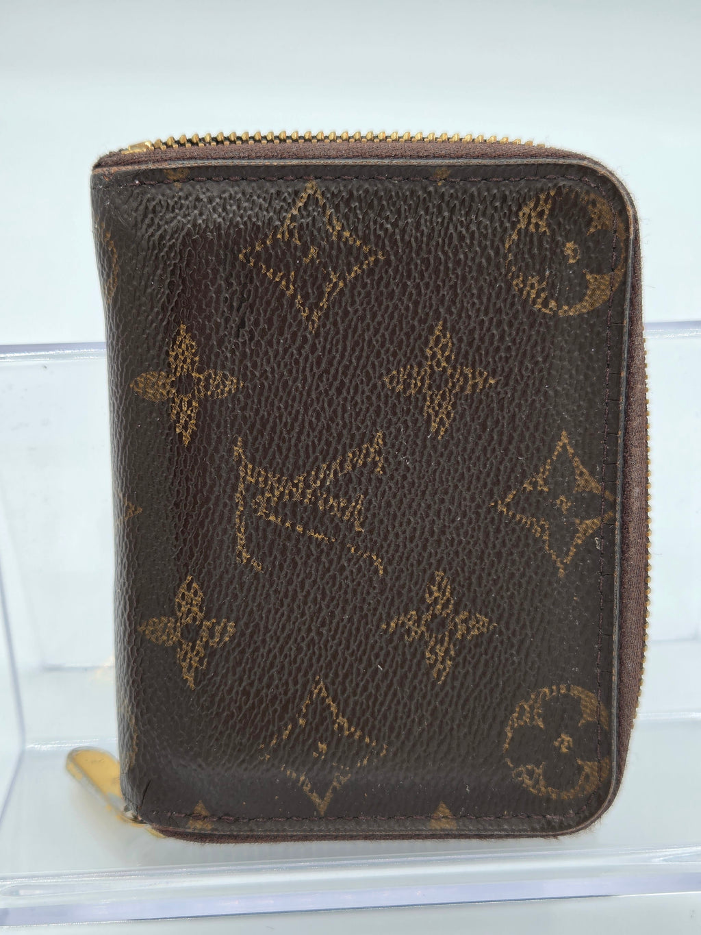 Brown wallet with gold monogram pattern on a white background
