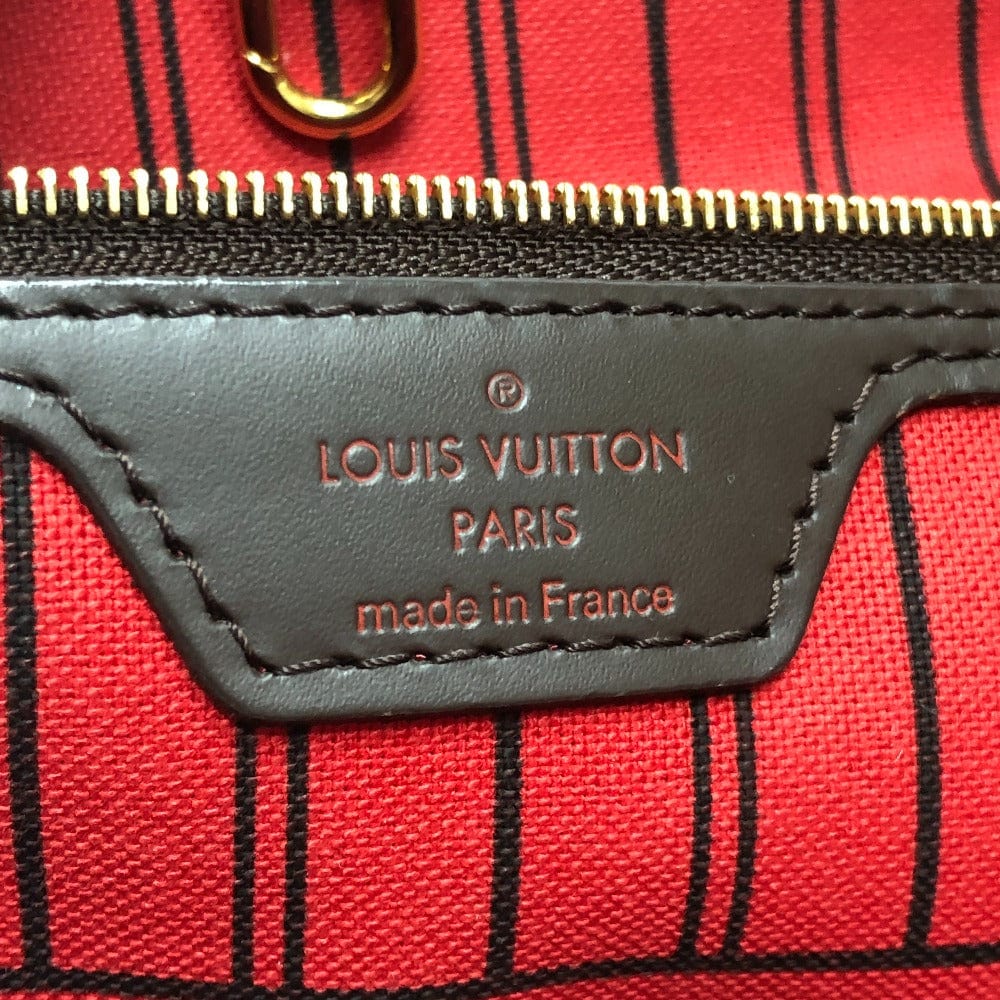 Louis Vuitton bag with red plaid pattern and gold zipper.