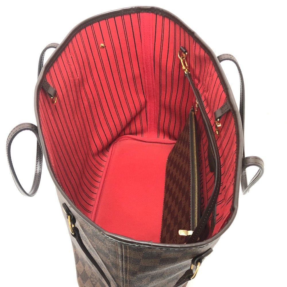 Open handbag revealing a red interior with gold zippers on a white background