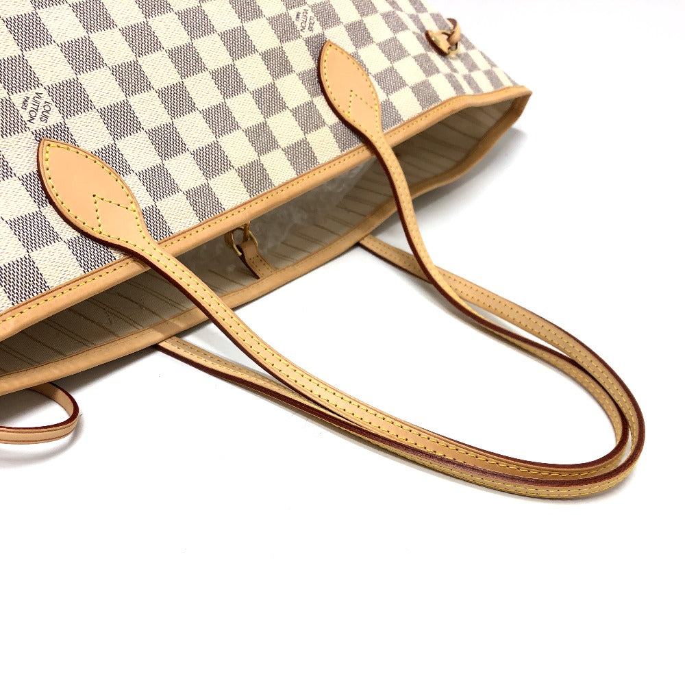 Designer handbag with checkered pattern and tan leather handle on a white background