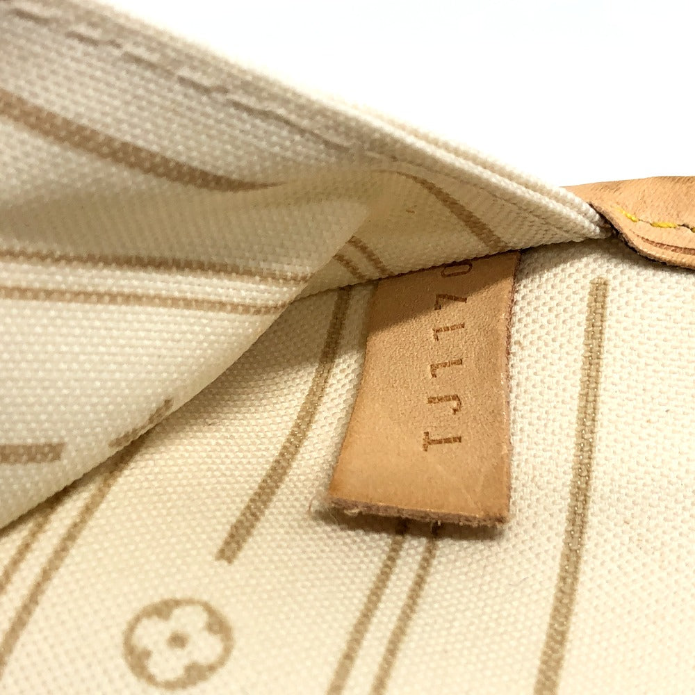 Close-up of a beige fabric surface with a brown leather tag displaying 'ALLI'.