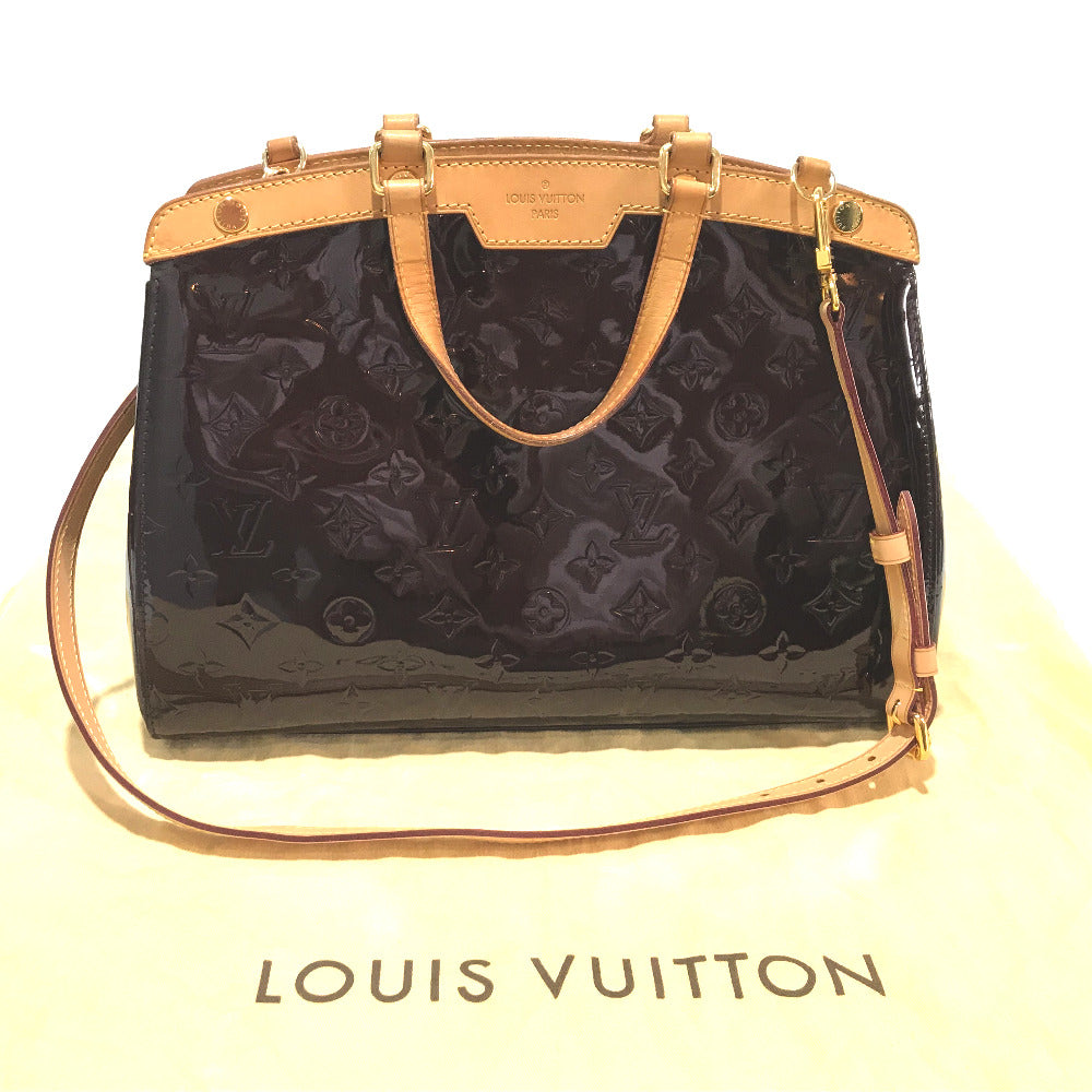 Louis Vuitton handbag with black monogram pattern and gold accents on a white background