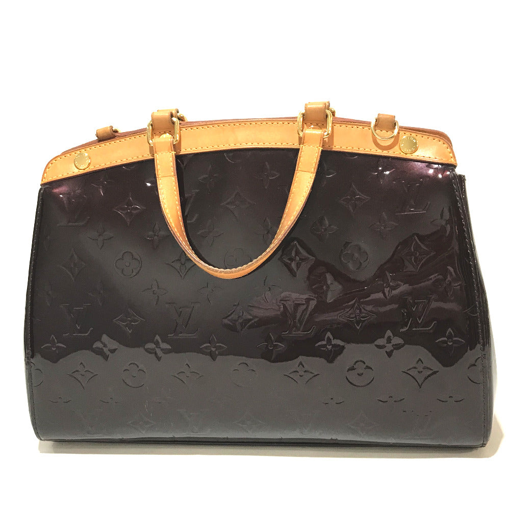 Black handbag with gold handles and accents on a white background