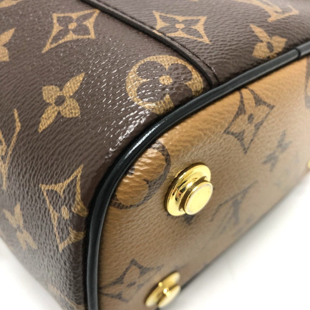 Close-up of a brown handbag with gold monogram pattern and gold hardware.