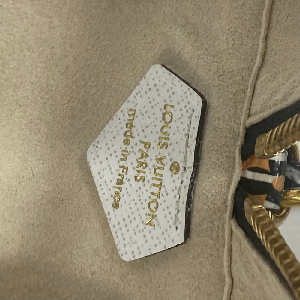 Louis Vuitton label on a beige handbag with gold hardware.