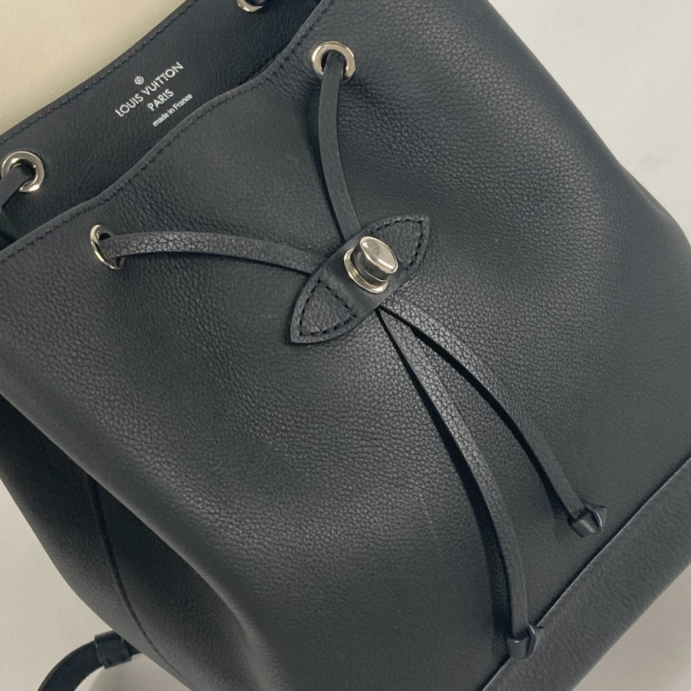 Close-up of a black leather bag with visible brand logo on a light gray background