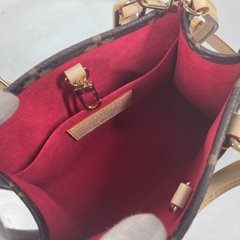 Close-up of a red handbag with gold hardware on a light gray background
