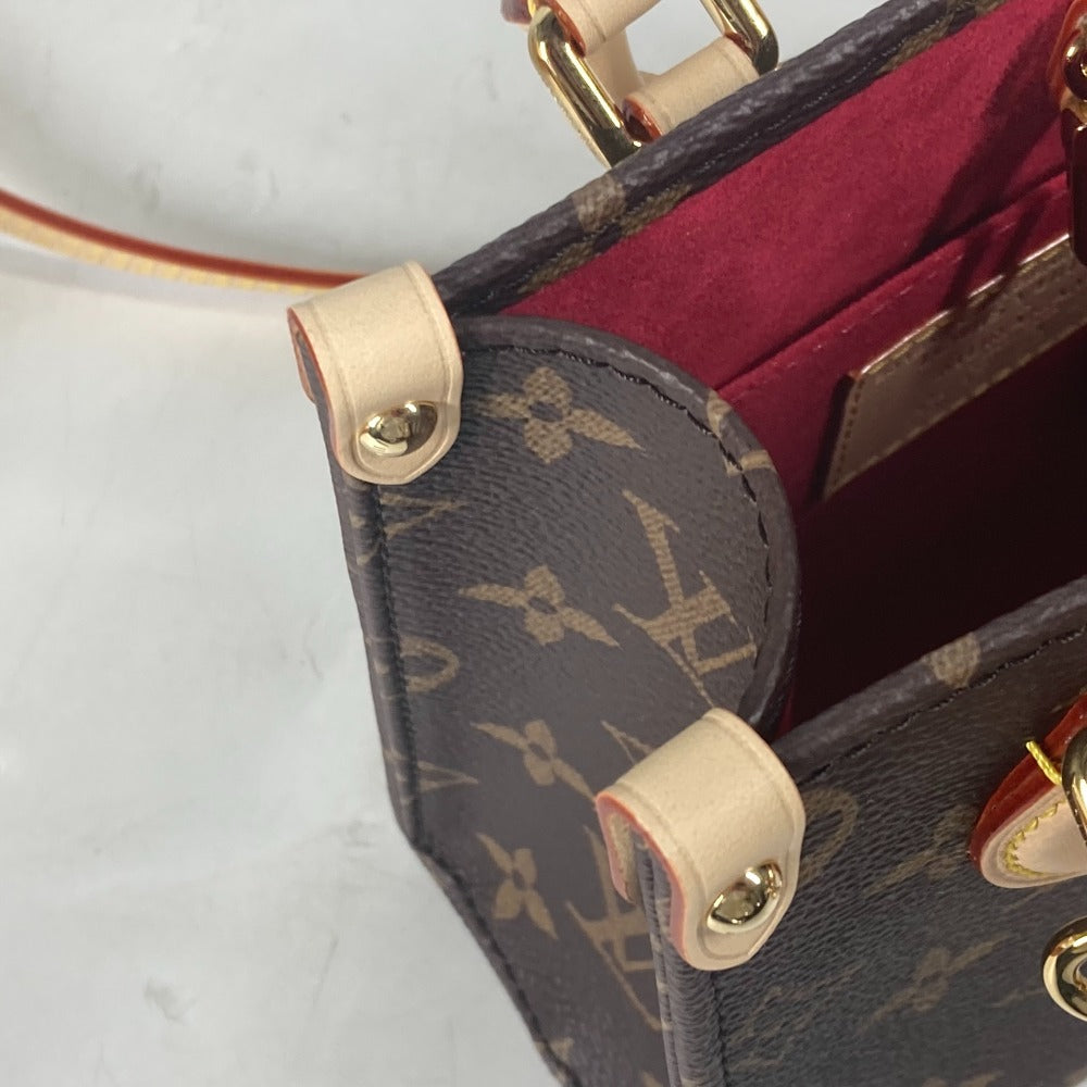 Close-up of a handbag with monogram pattern and gold hardware on a light background