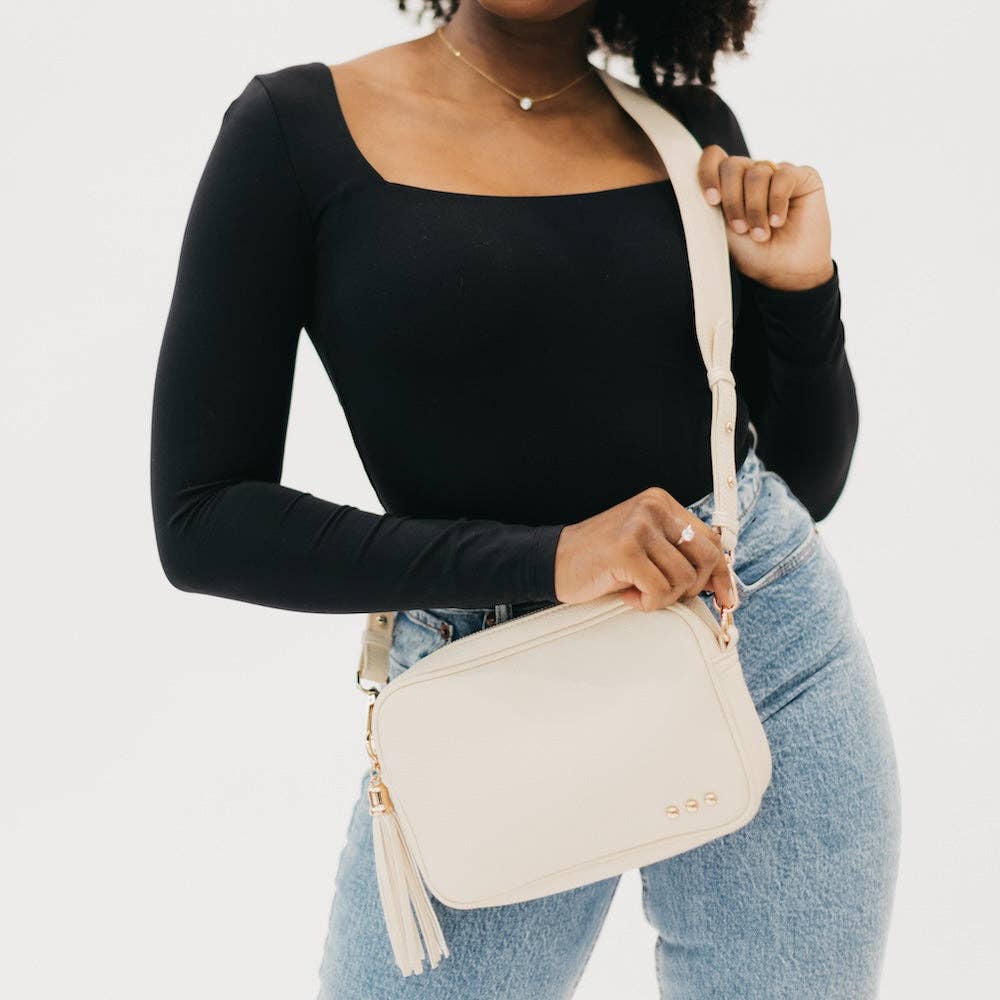 Person holding a beige handbag against a plain background