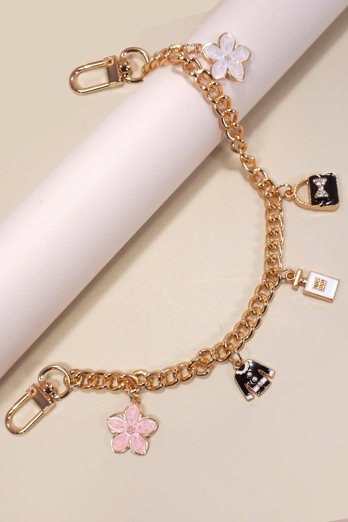 Gold bracelet with floral charms on a beige background