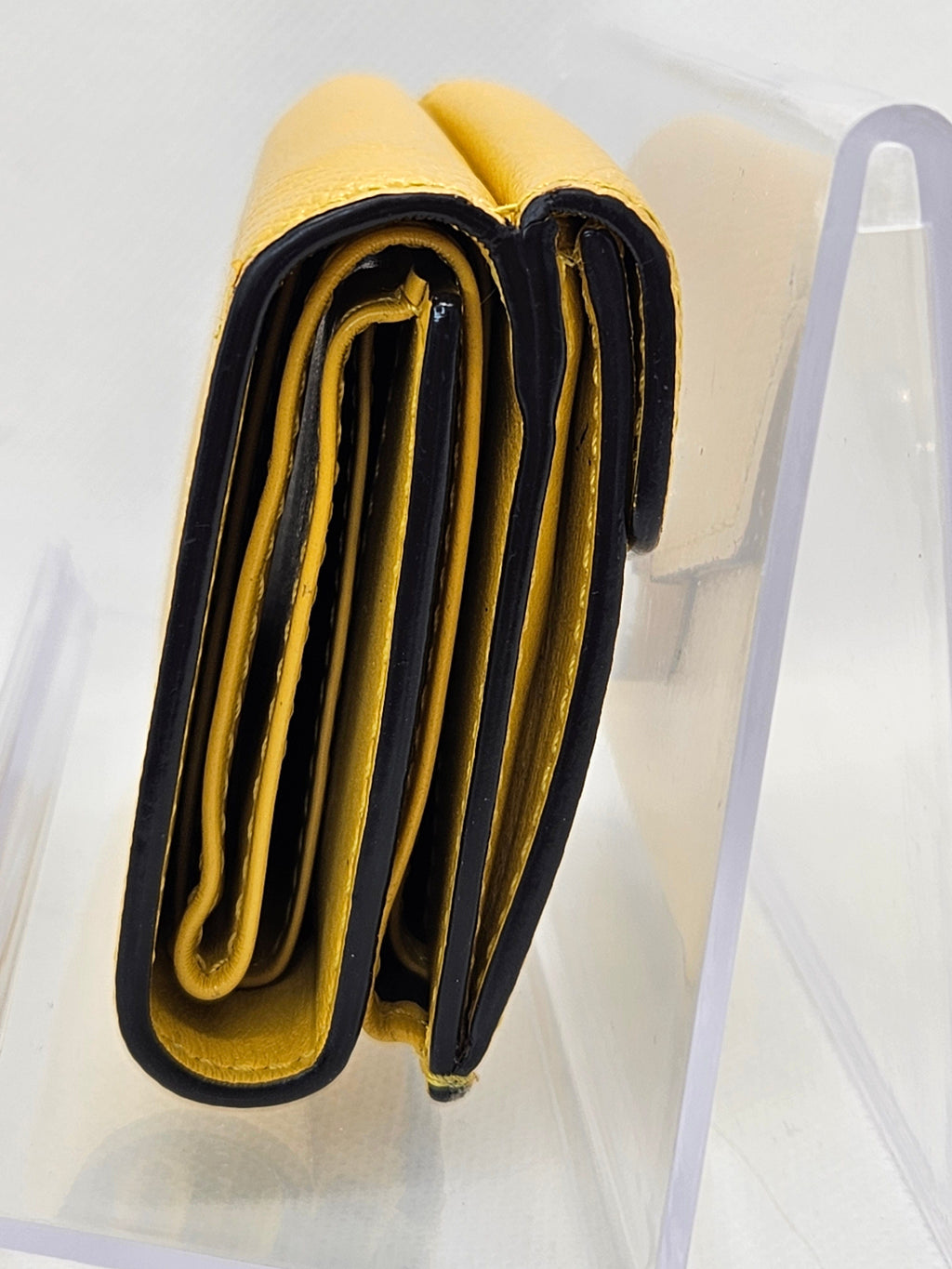 Yellow and black wallet on a clear stand