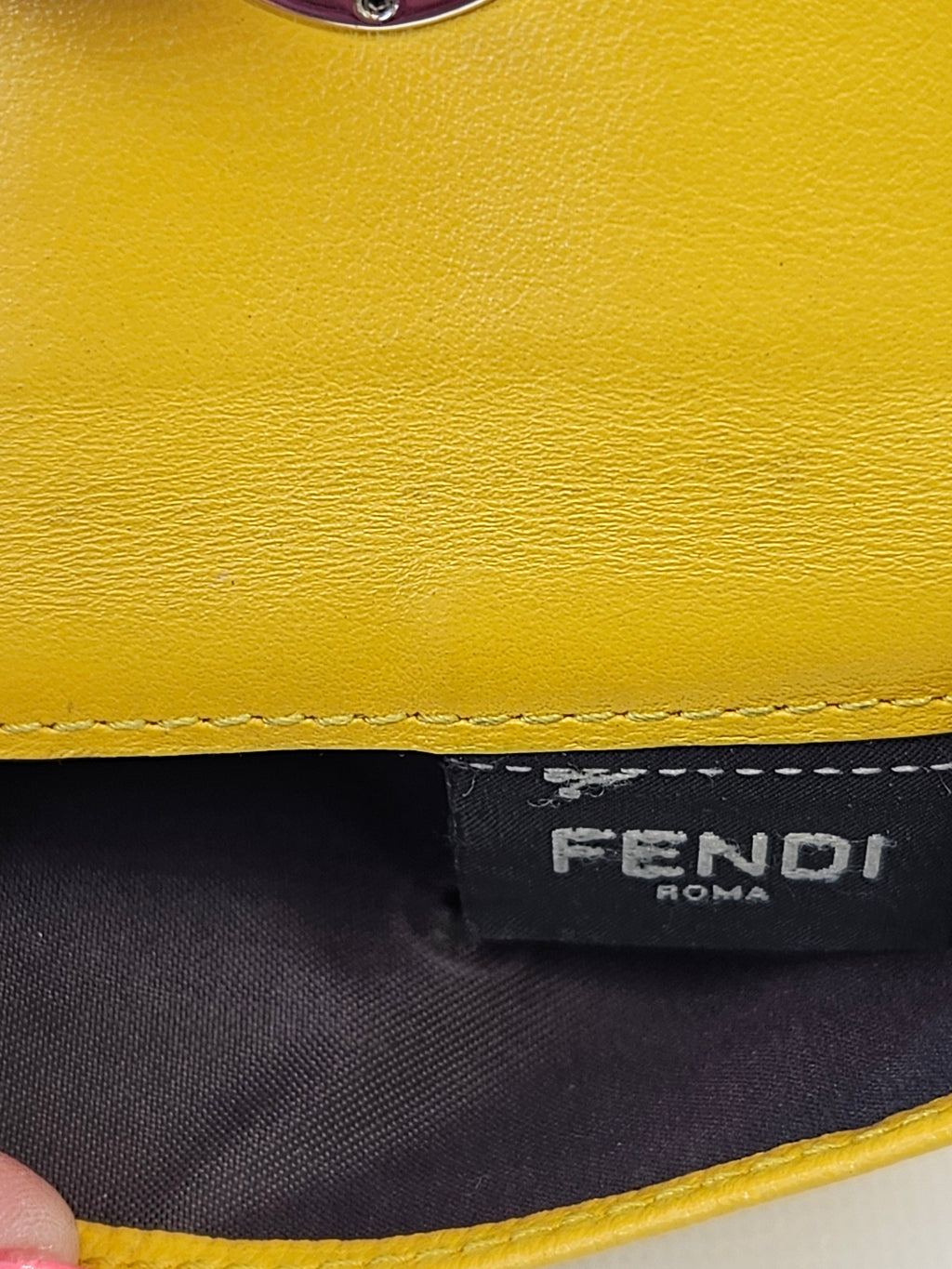 Close-up of a yellow leather product with 'Fendi' branding.