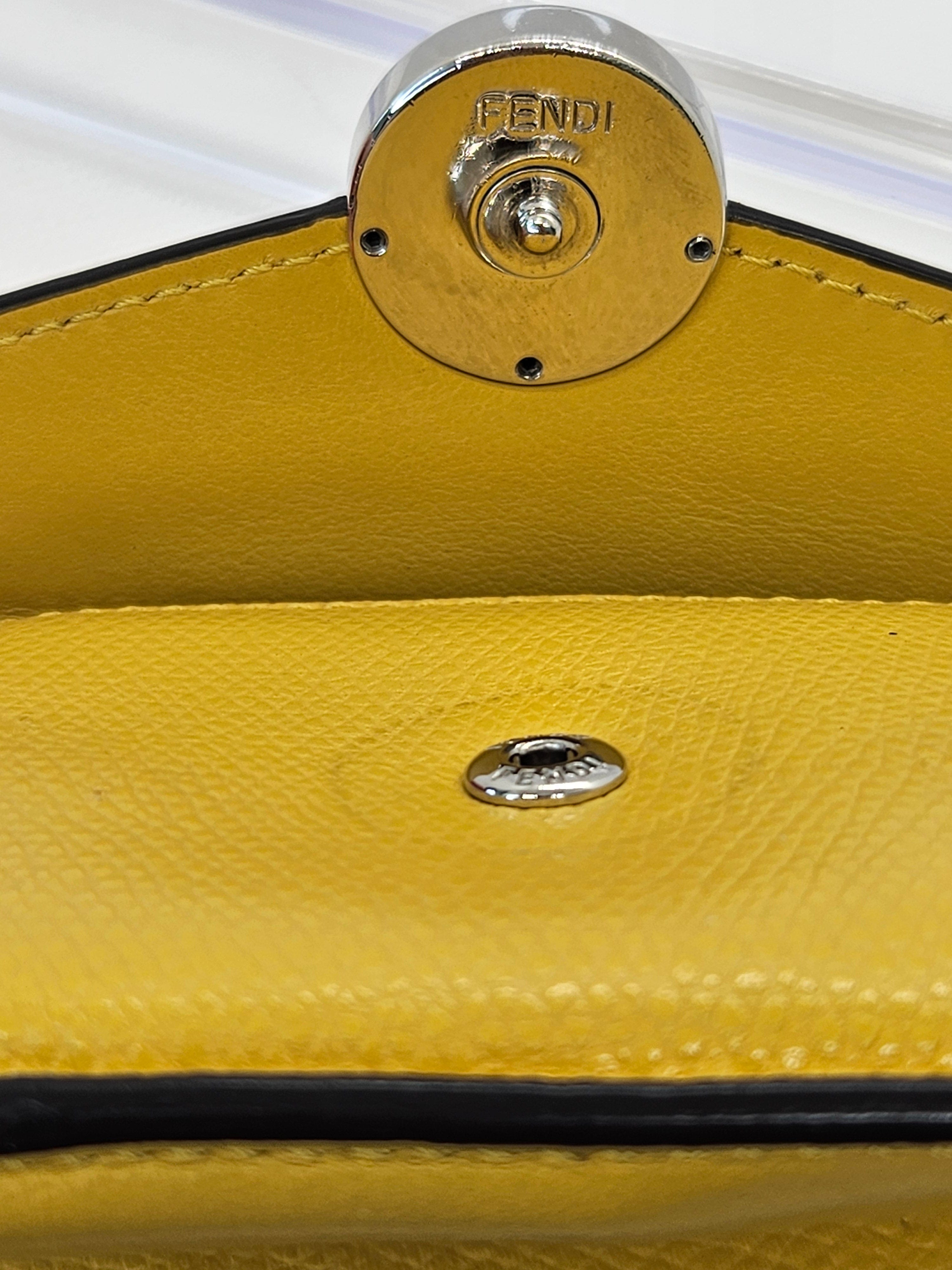 Close-up of a yellow handbag with a metallic clasp featuring the Fendi logo.