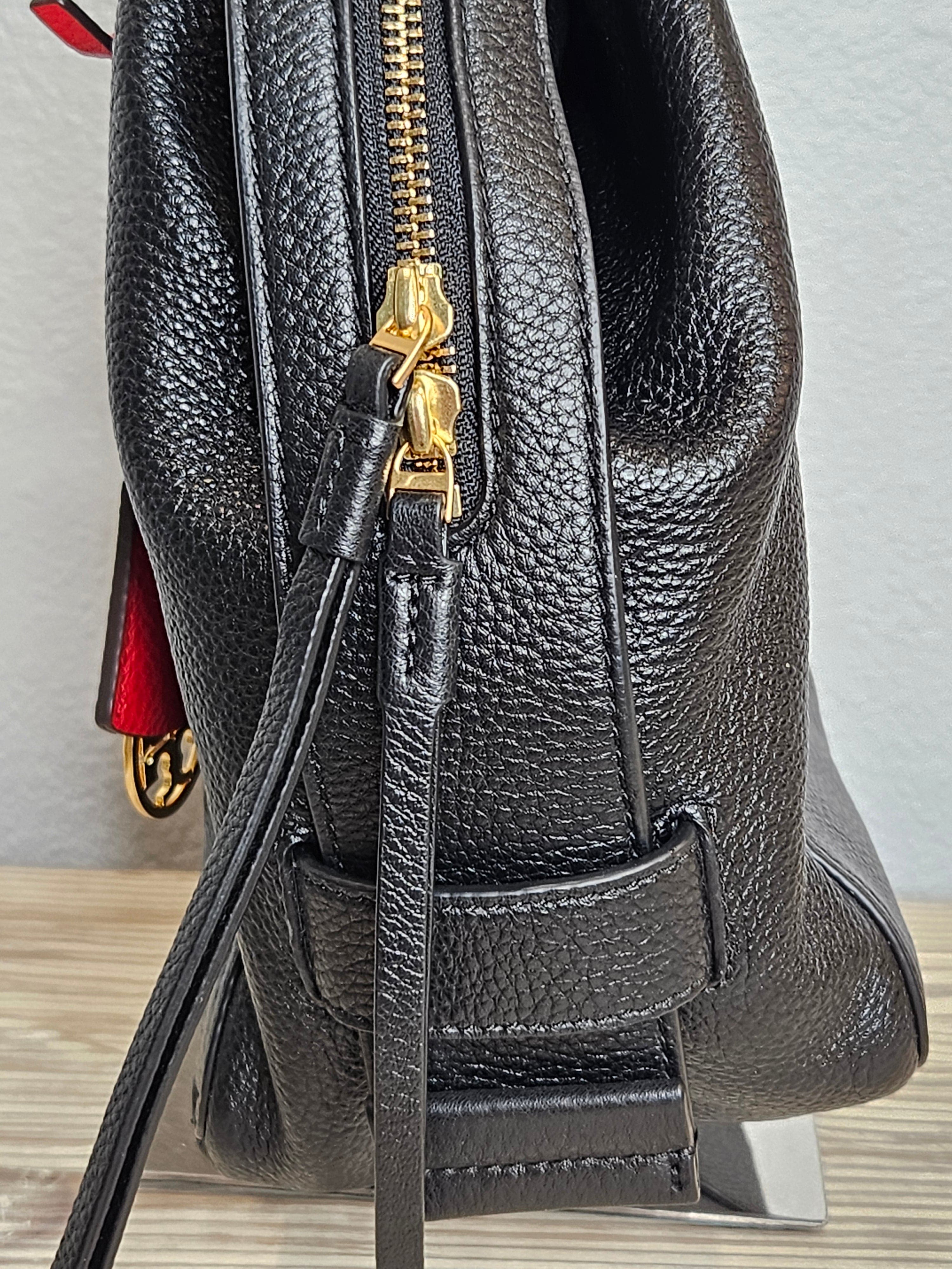 Close-up of a black leather handbag with gold zipper and handle.