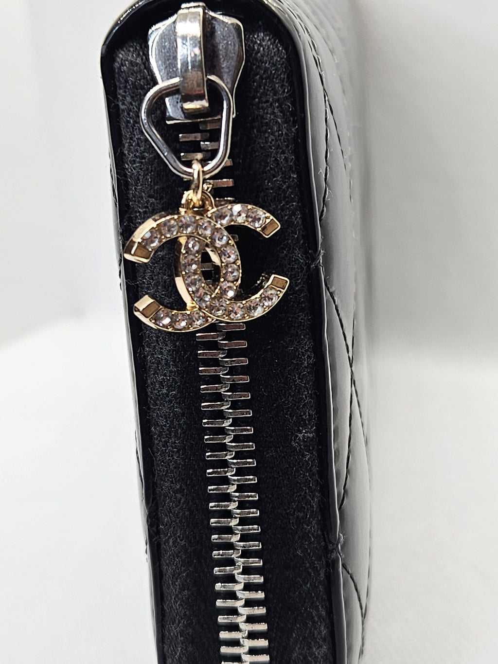 Chanel bag charm on a black quilted handbag with a white background