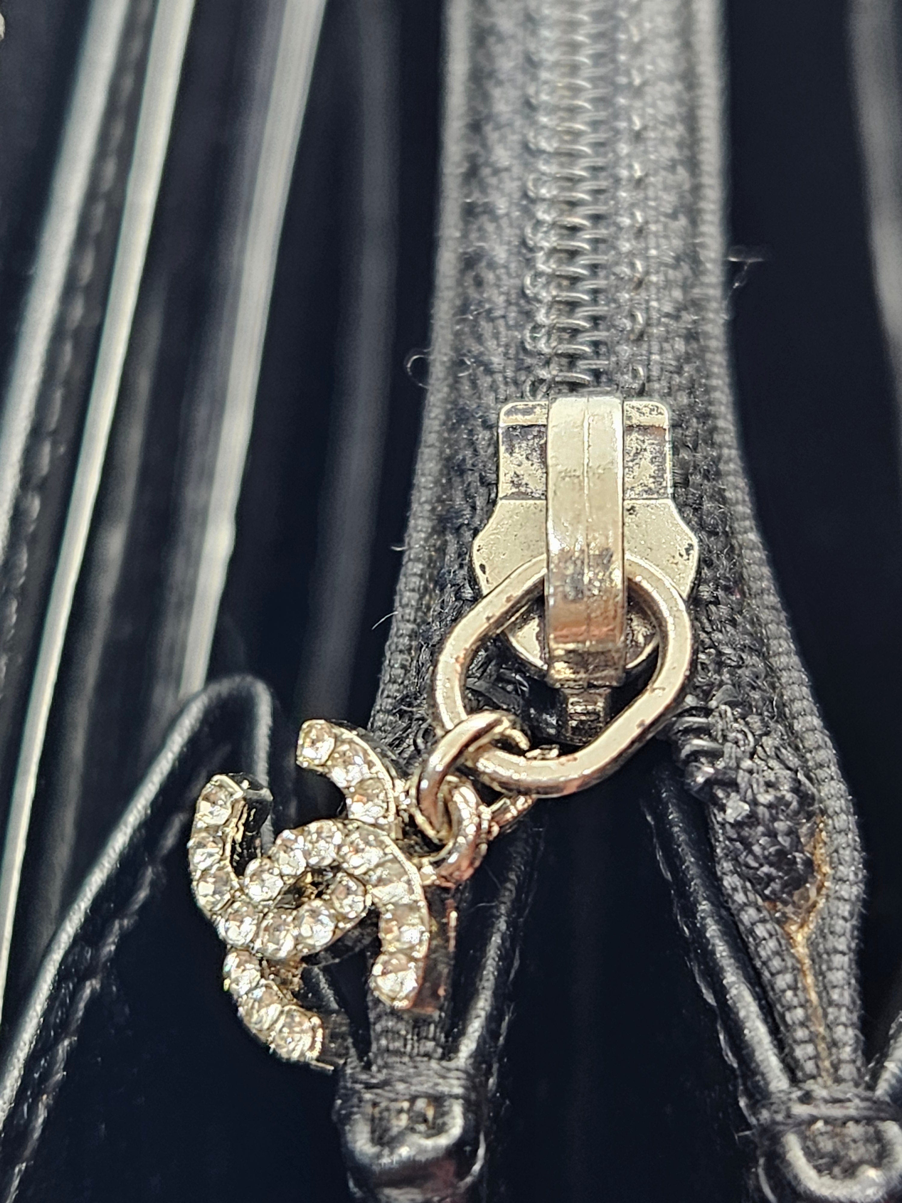 Chanel logo charm on a black leather bag with a zipper