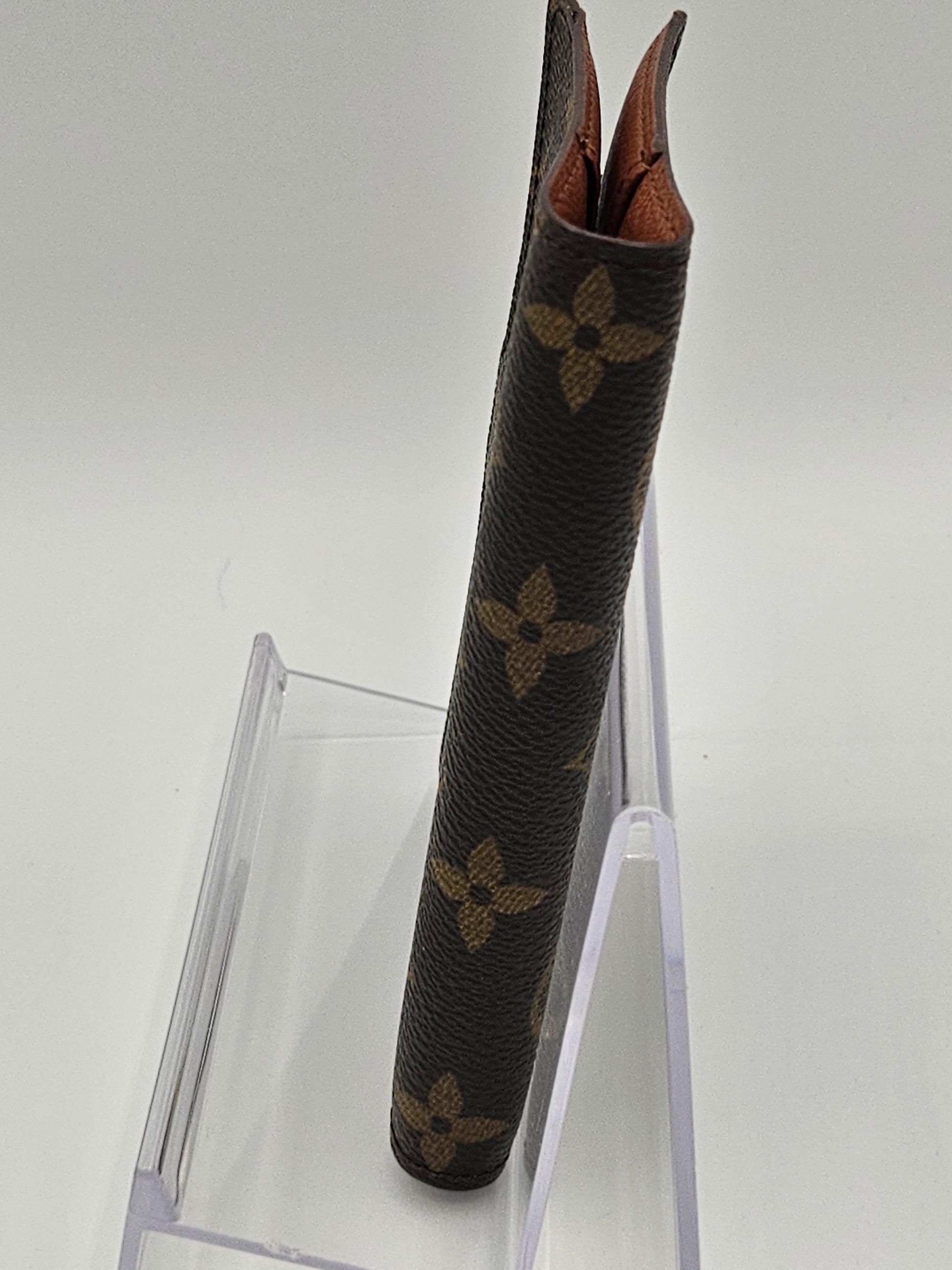 Louis Vuitton handbag handle on a clear stand against a white background