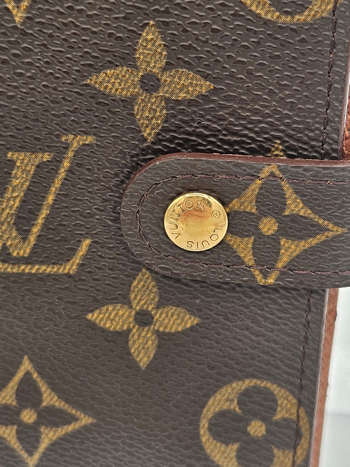 Close-up of a Louis Vuitton handbag with monogram pattern and gold emblem.