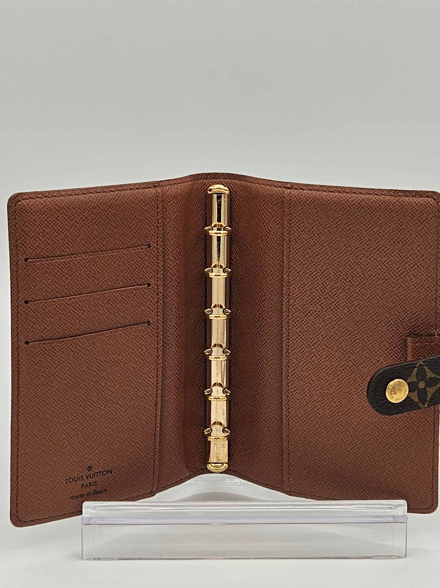 Brown leather planner with gold ring binding on a gray background