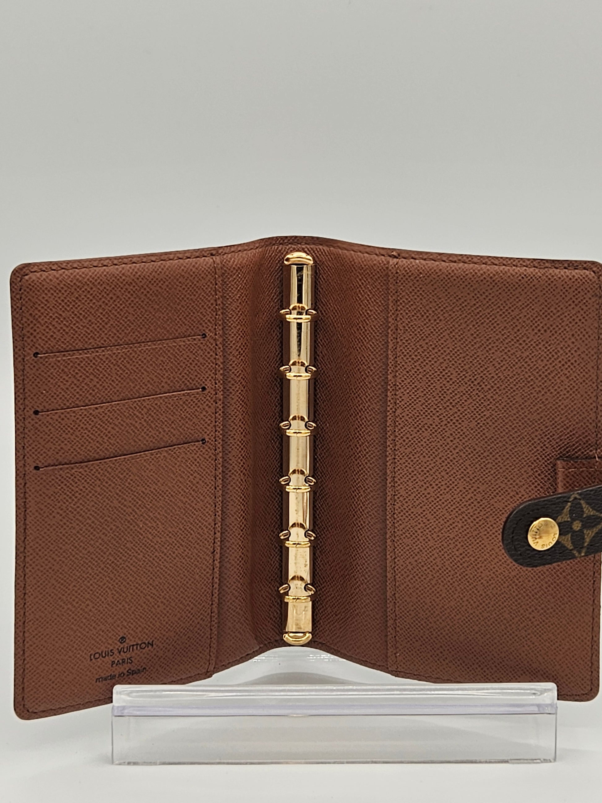 Brown leather planner with gold ring binding on a gray background