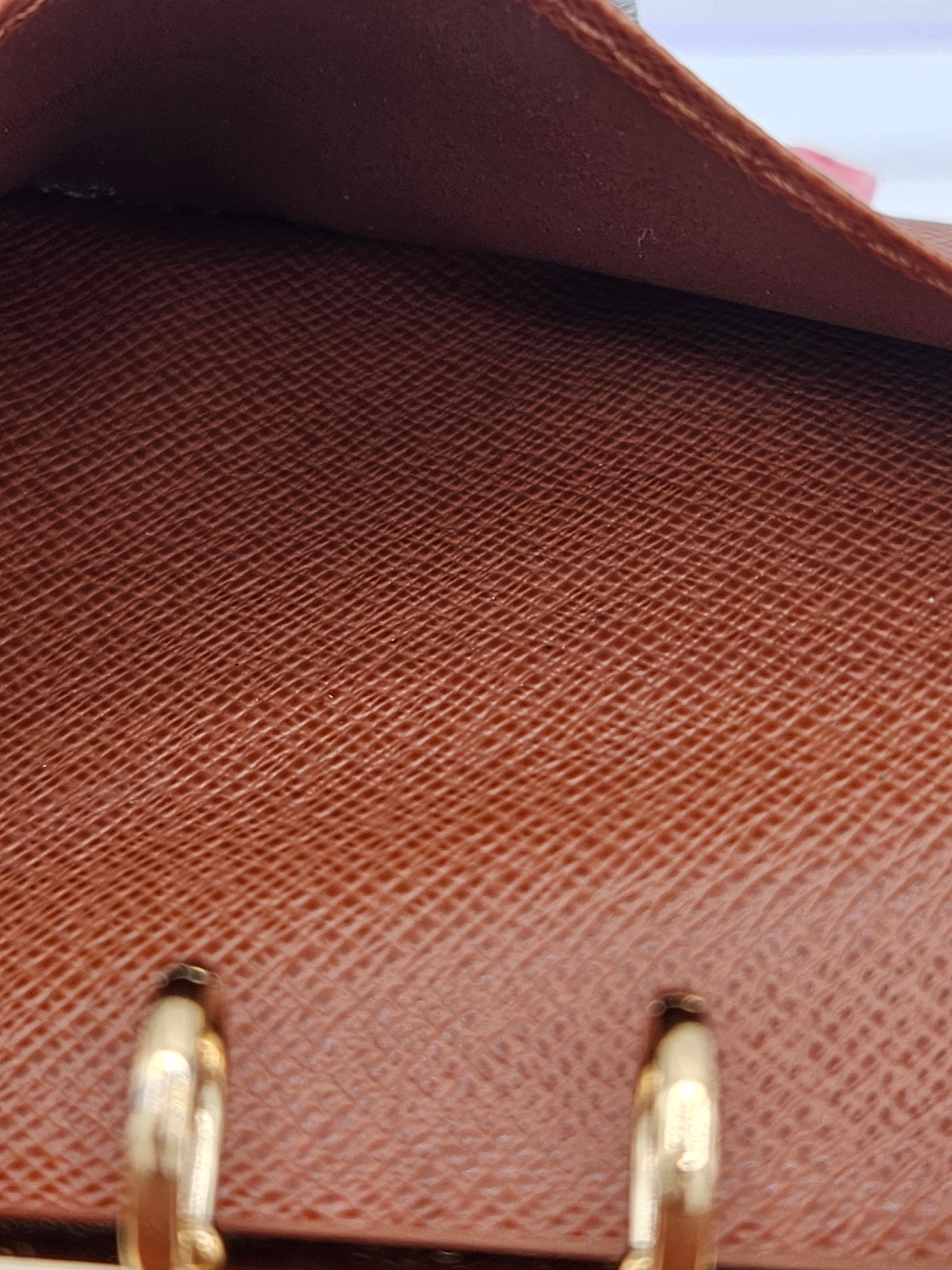 Close-up of a brown textured handbag with gold hardware.