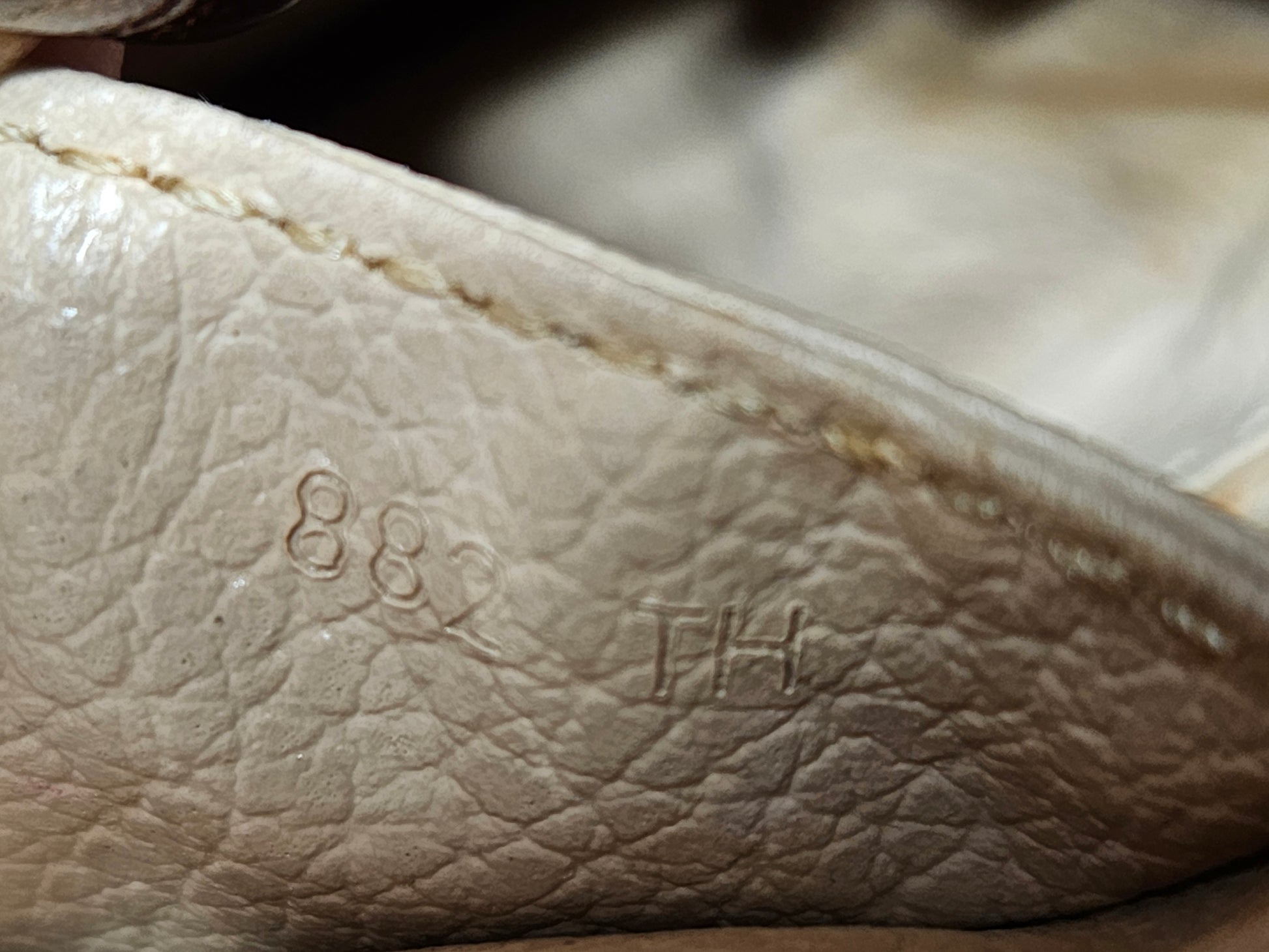 Close-up of beige leather surface with visible branding.