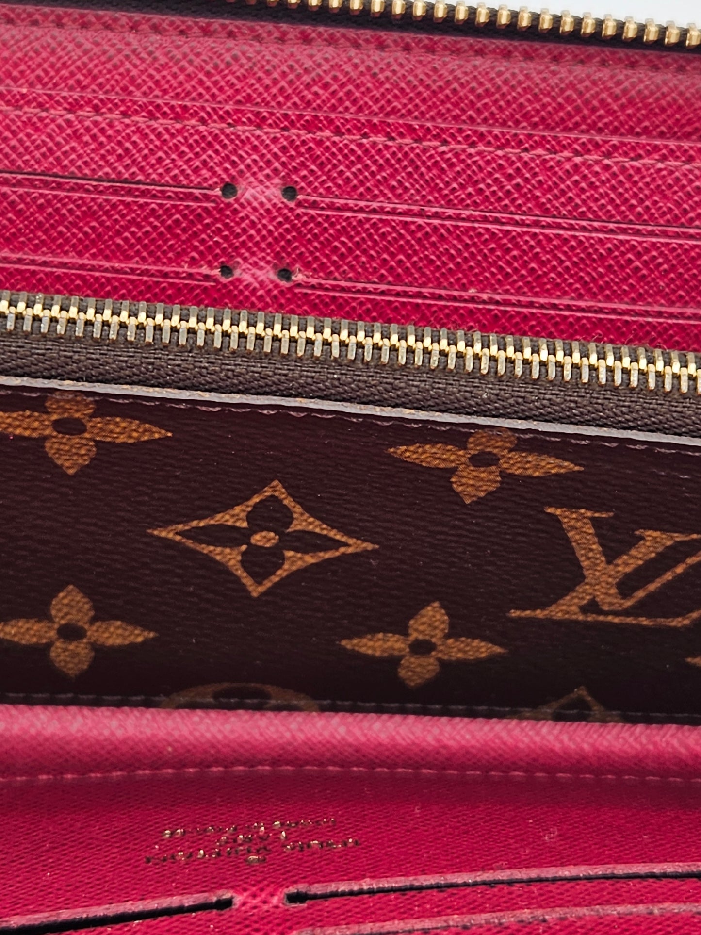 Close-up of a pink and brown Louis Vuitton wallet with gold zipper.