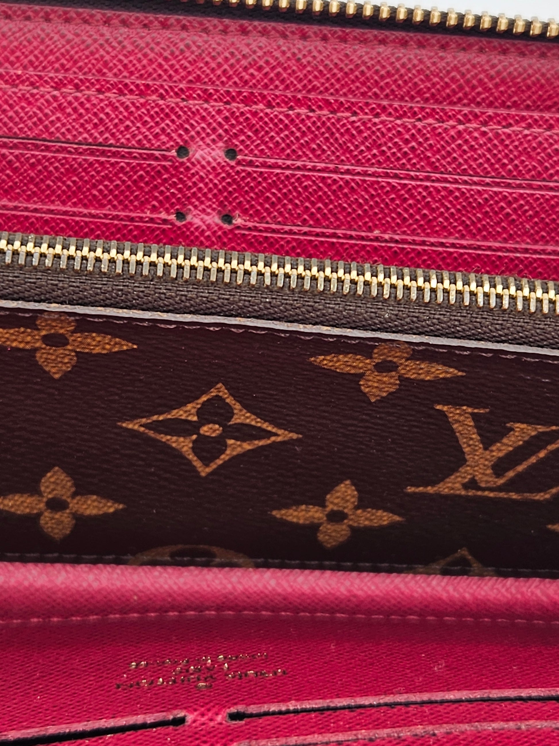 Close-up of a pink and brown Louis Vuitton wallet with gold zipper.