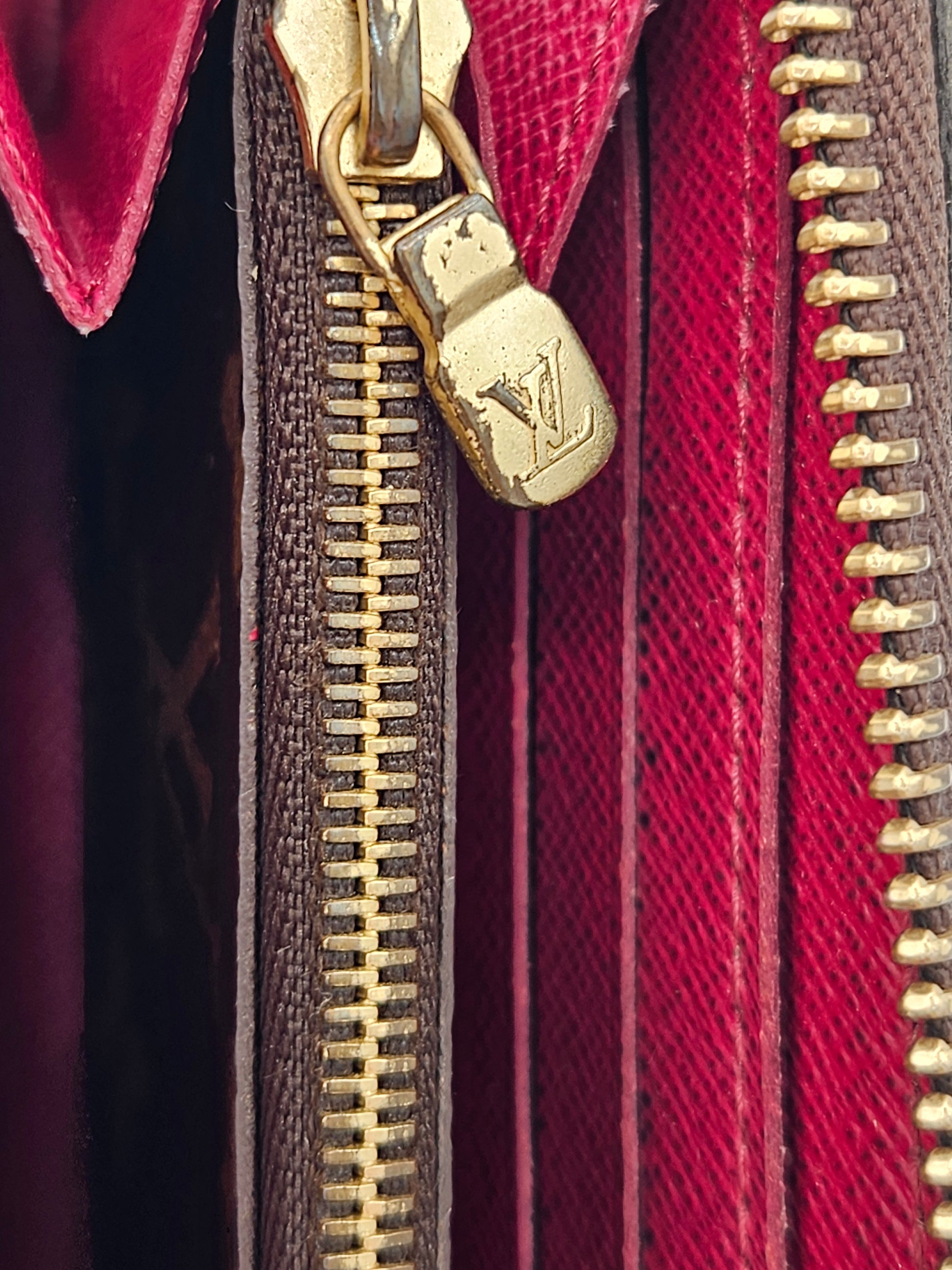 Close-up of a gold zipper on a red and brown textured surface