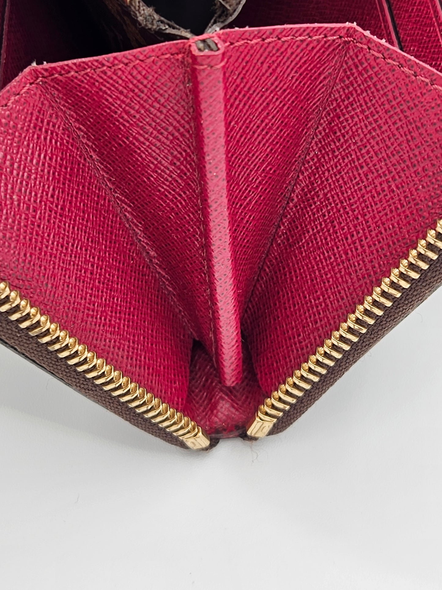 Close-up of a red wallet with gold zipper on a white background