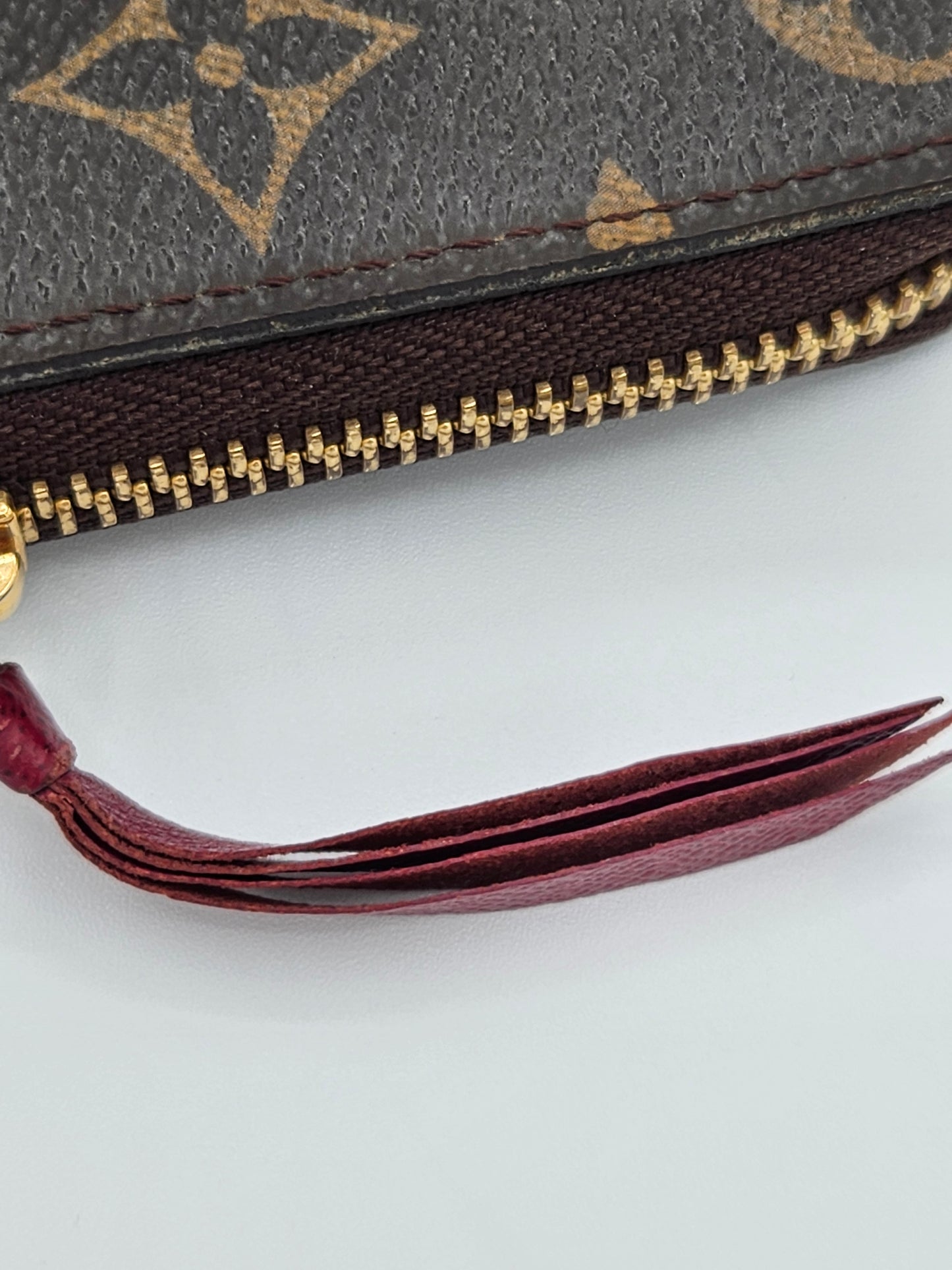 Close-up of a Louis Vuitton wallet with a visible logo and zipper, on a white background.