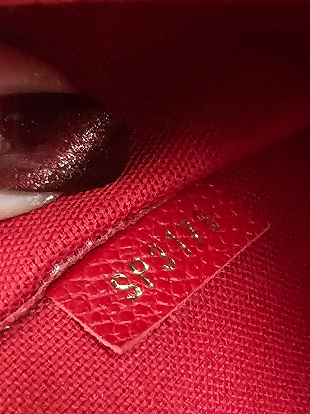 Close-up of a red fabric with a brand logo, held by a hand.