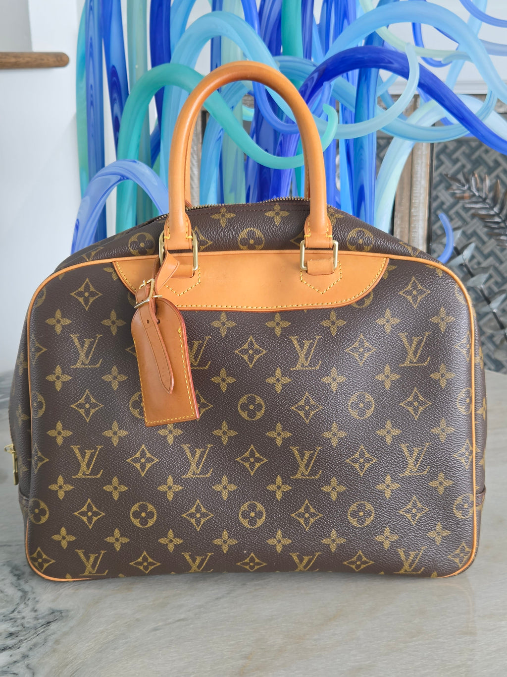 Designer handbag with monogram pattern against a blurred background