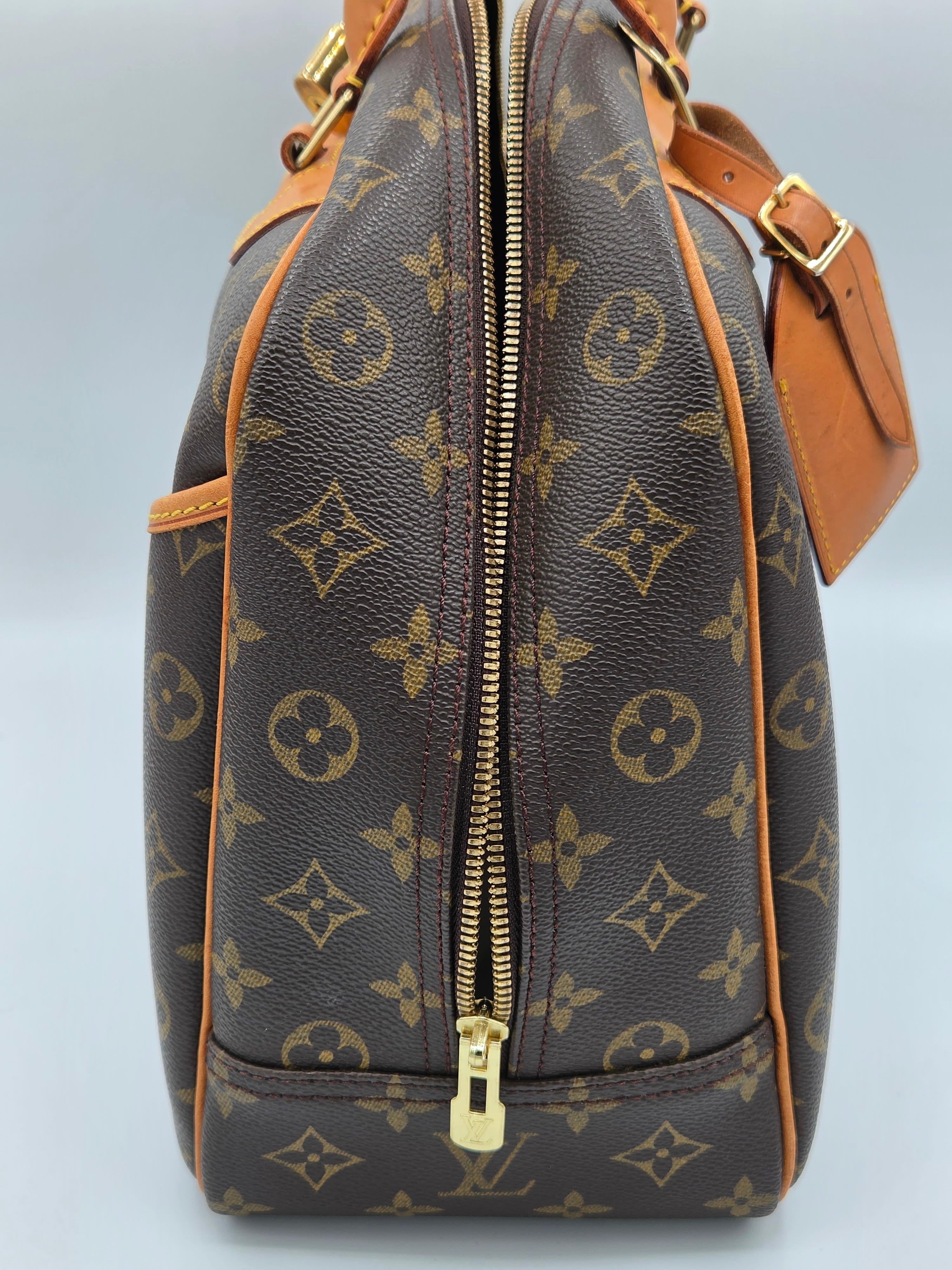 Brown leather bag with gold monogram pattern on a light gray background