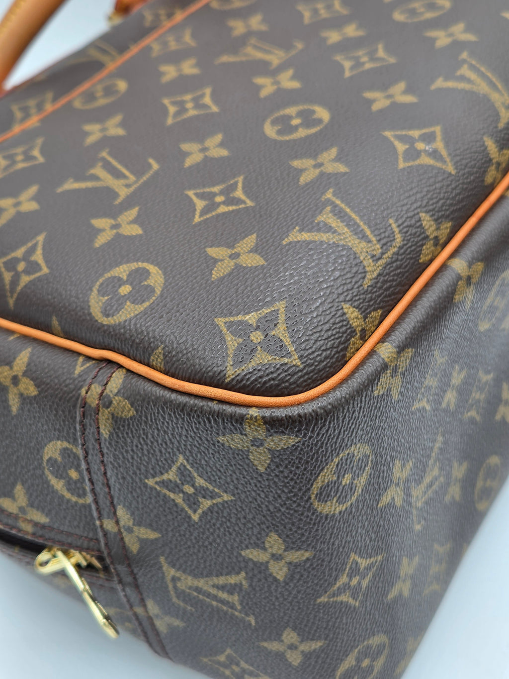 Close-up of a brown leather bag with gold monogram pattern