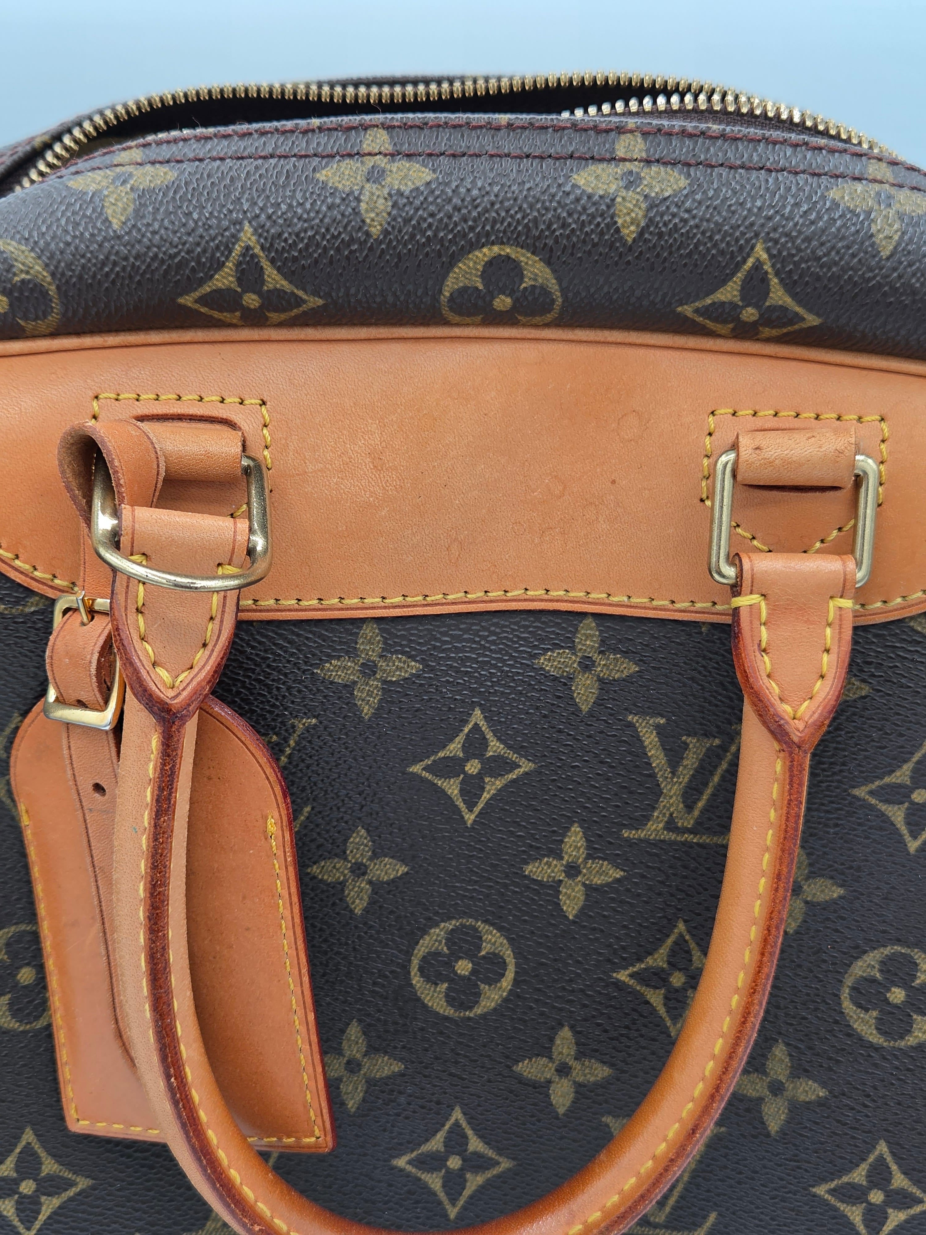 Close-up of a Louis Vuitton handbag with monogram pattern and brown leather handles.