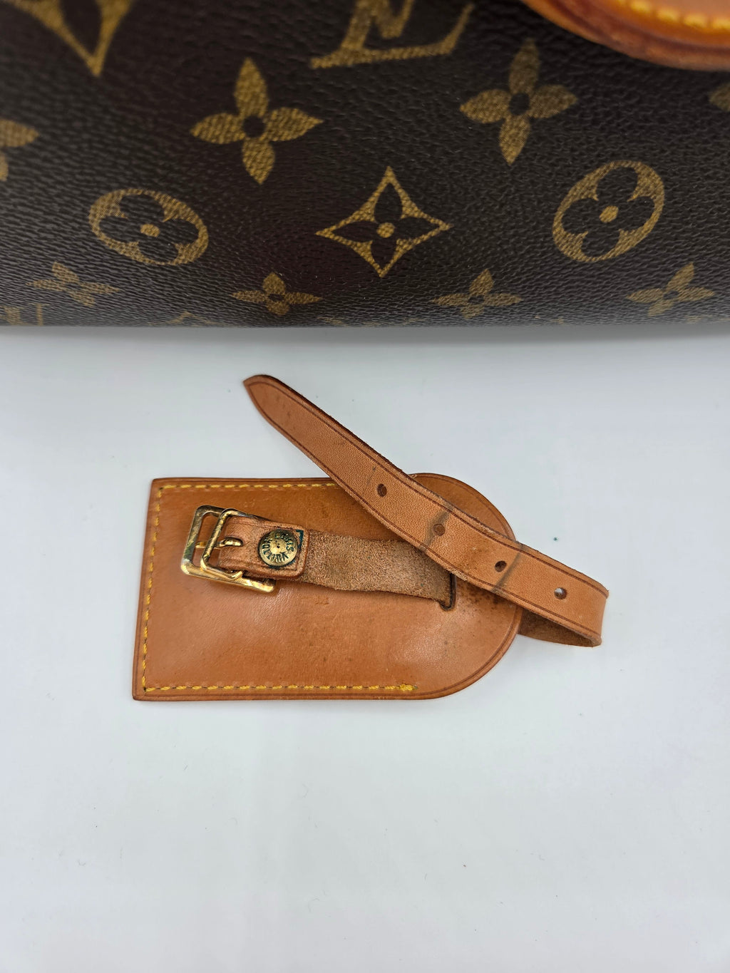 Brown leather luggage tag with gold buckle on a white background
