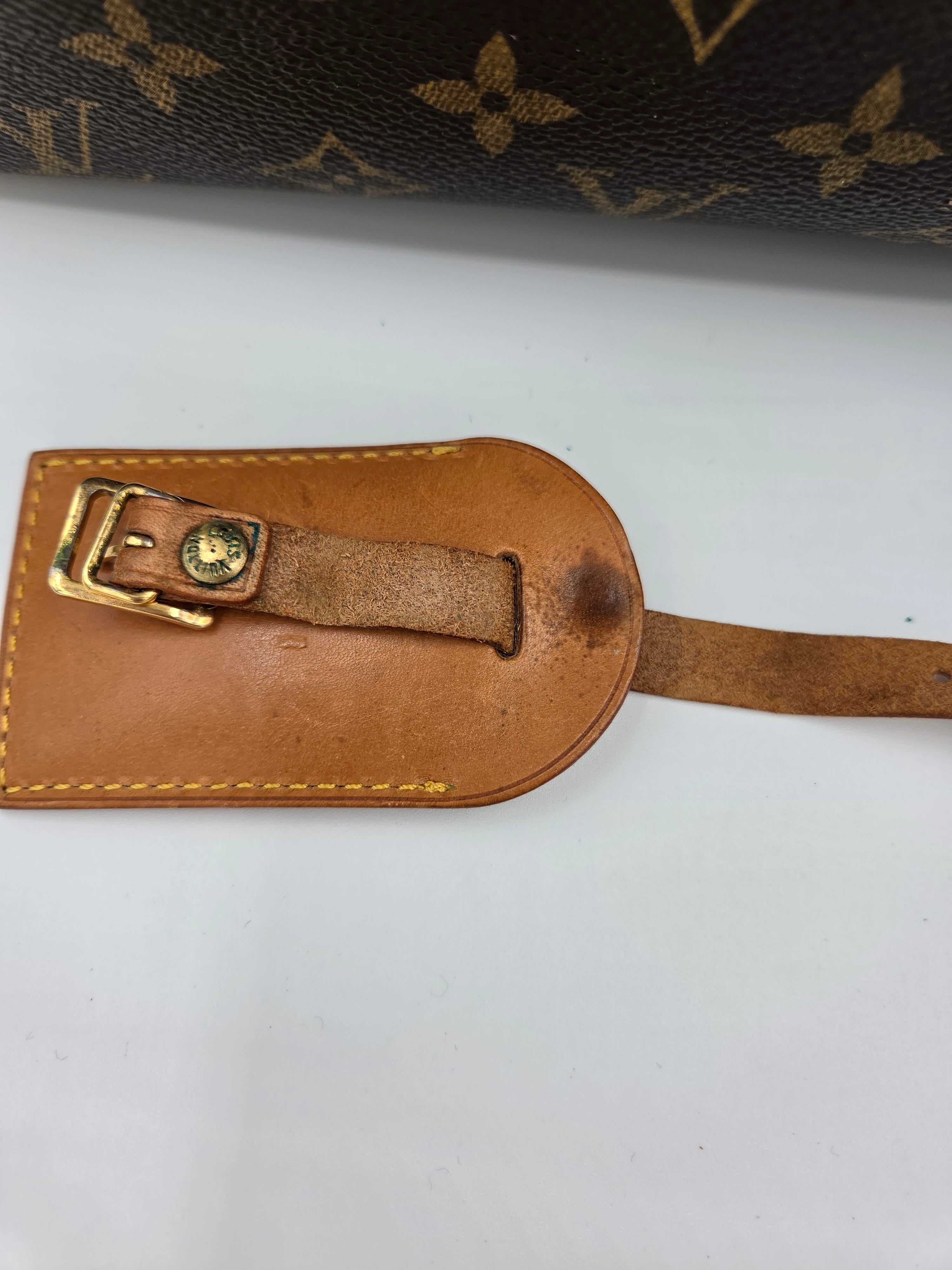 Brown leather luggage tag with gold buckle on a white background