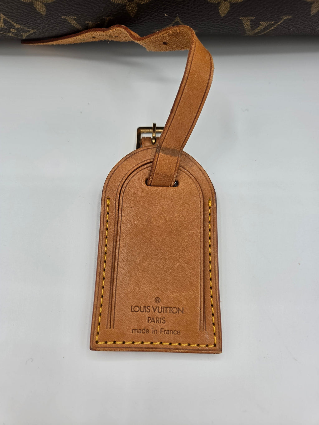 Brown Louis Vuitton luggage tag on a white background