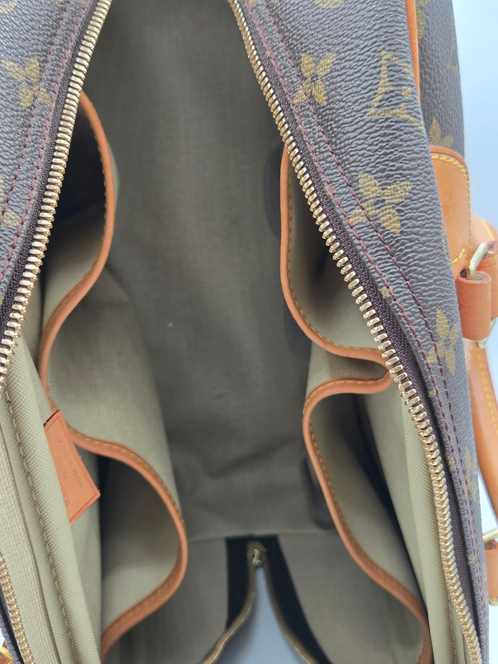 Close-up of a gray handbag with brown leather accents and a visible brand logo.