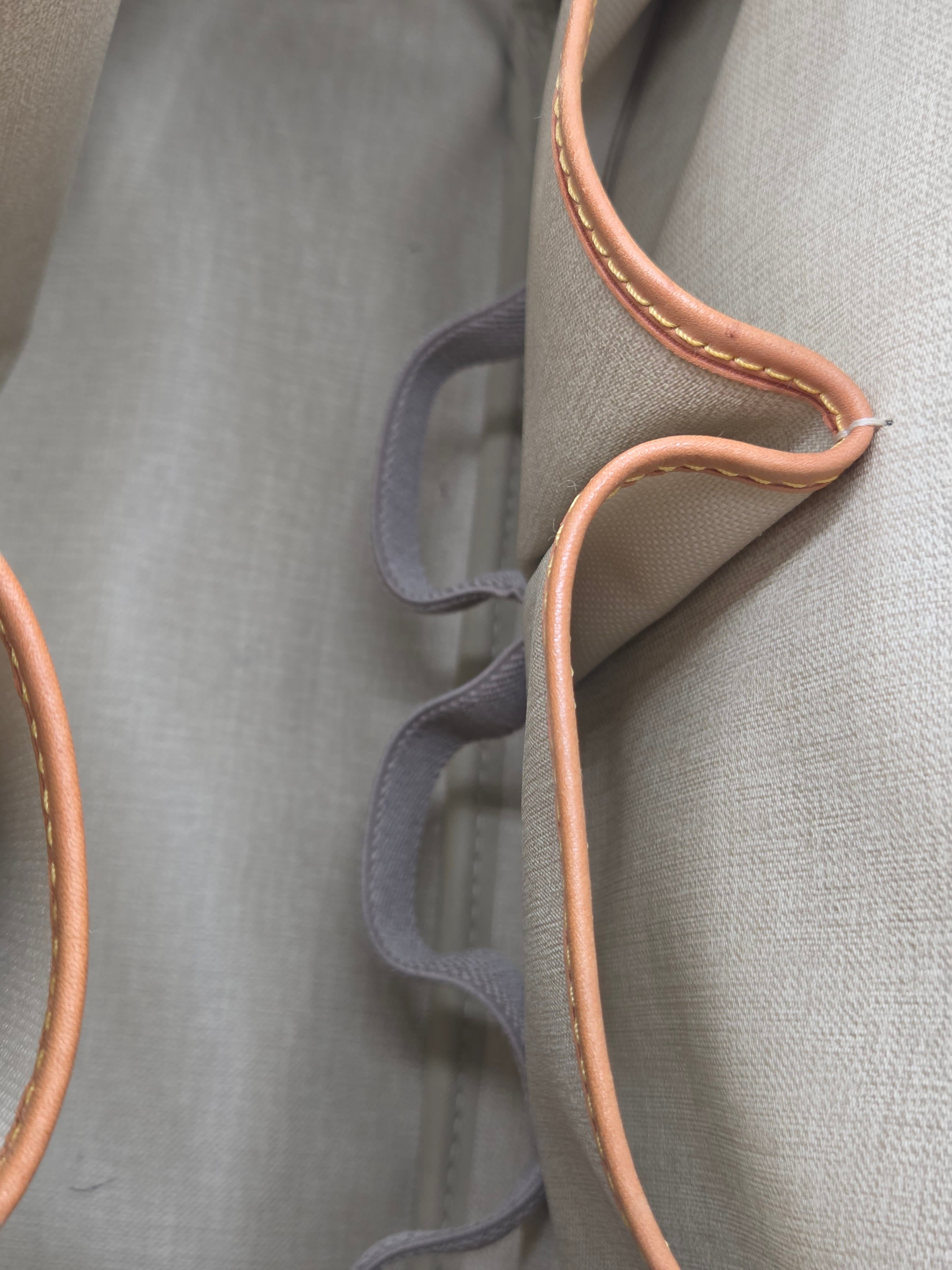 Close-up of a gray fabric surface with brown leather trim