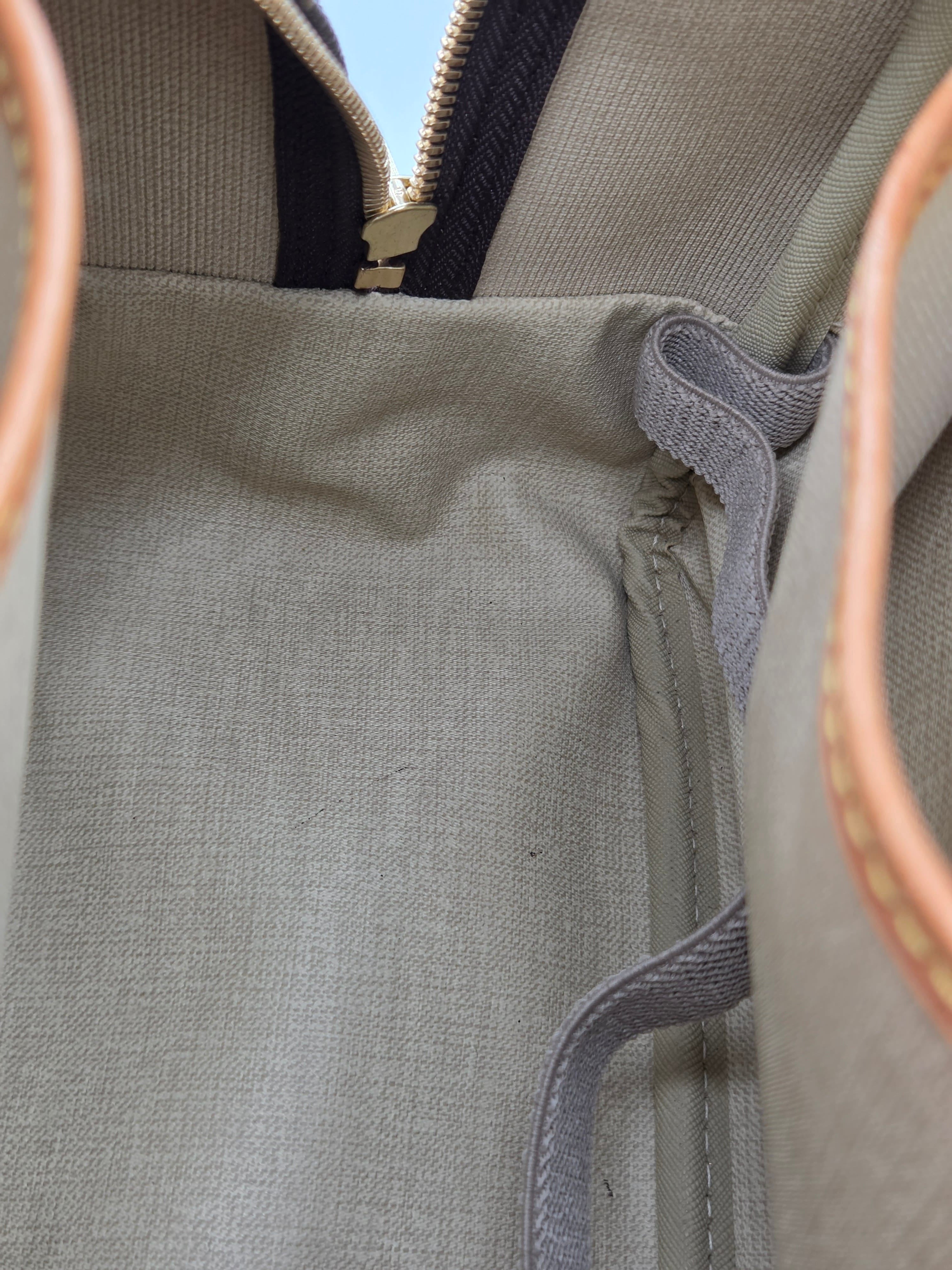 Close-up of a gray bag with leather handles and zipper