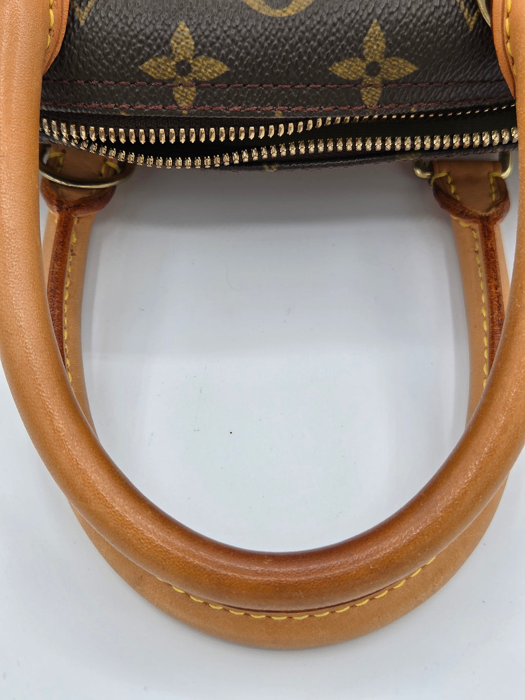 Close-up of a brown handbag with visible brand logo on a white background